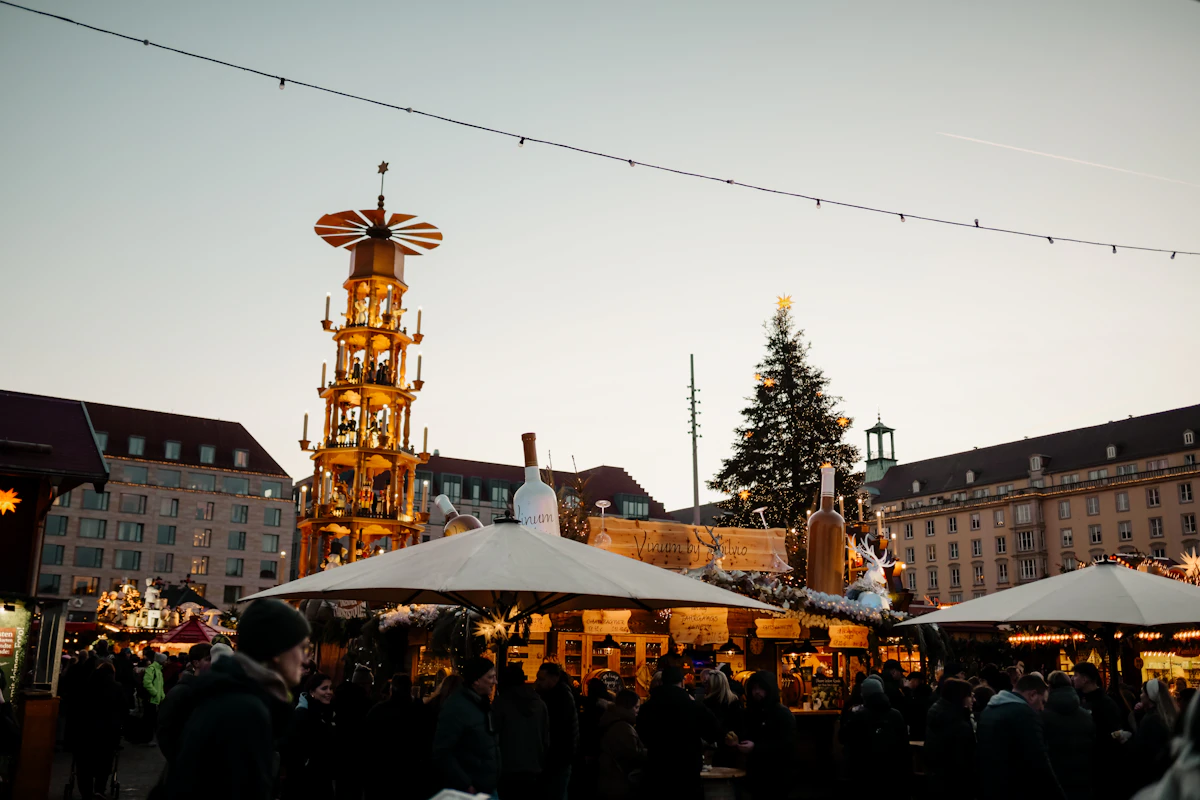 Marché de Noël sur une place avec ses chalets, une pyramide en bois illuminée et un grand sapin