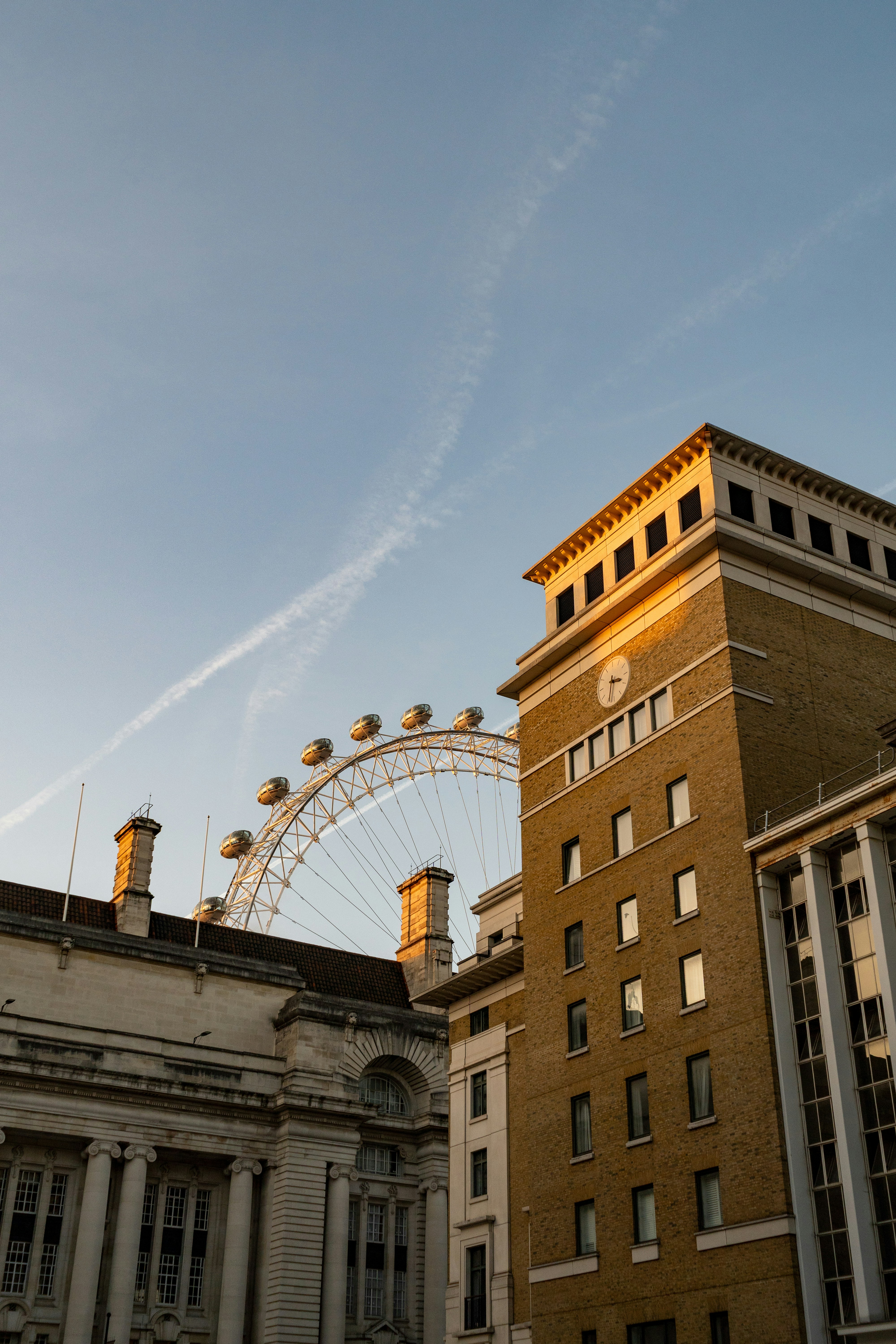 Ferris wheel behind buildings at sunset