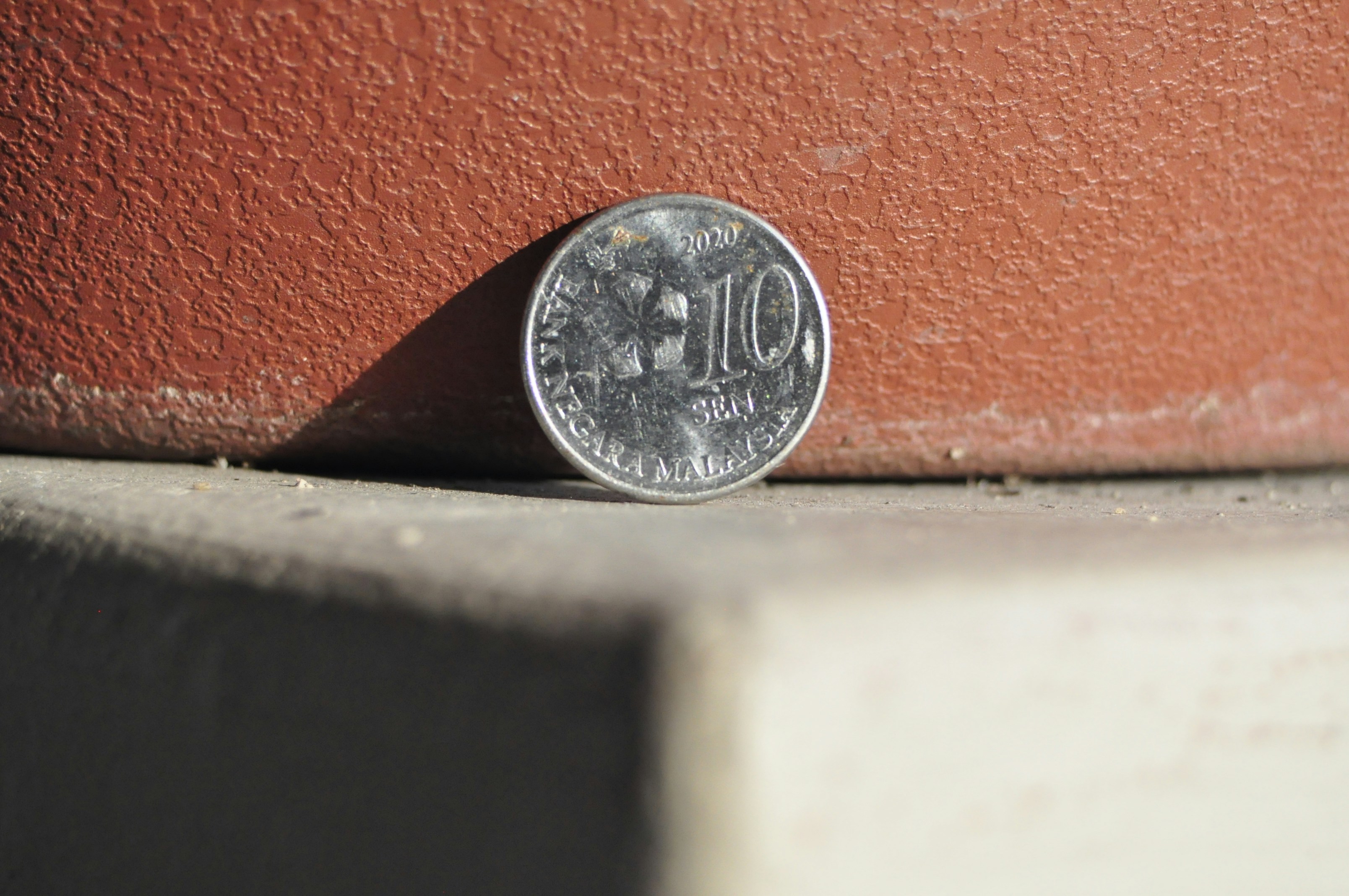 A single coin stands on a textured surface.