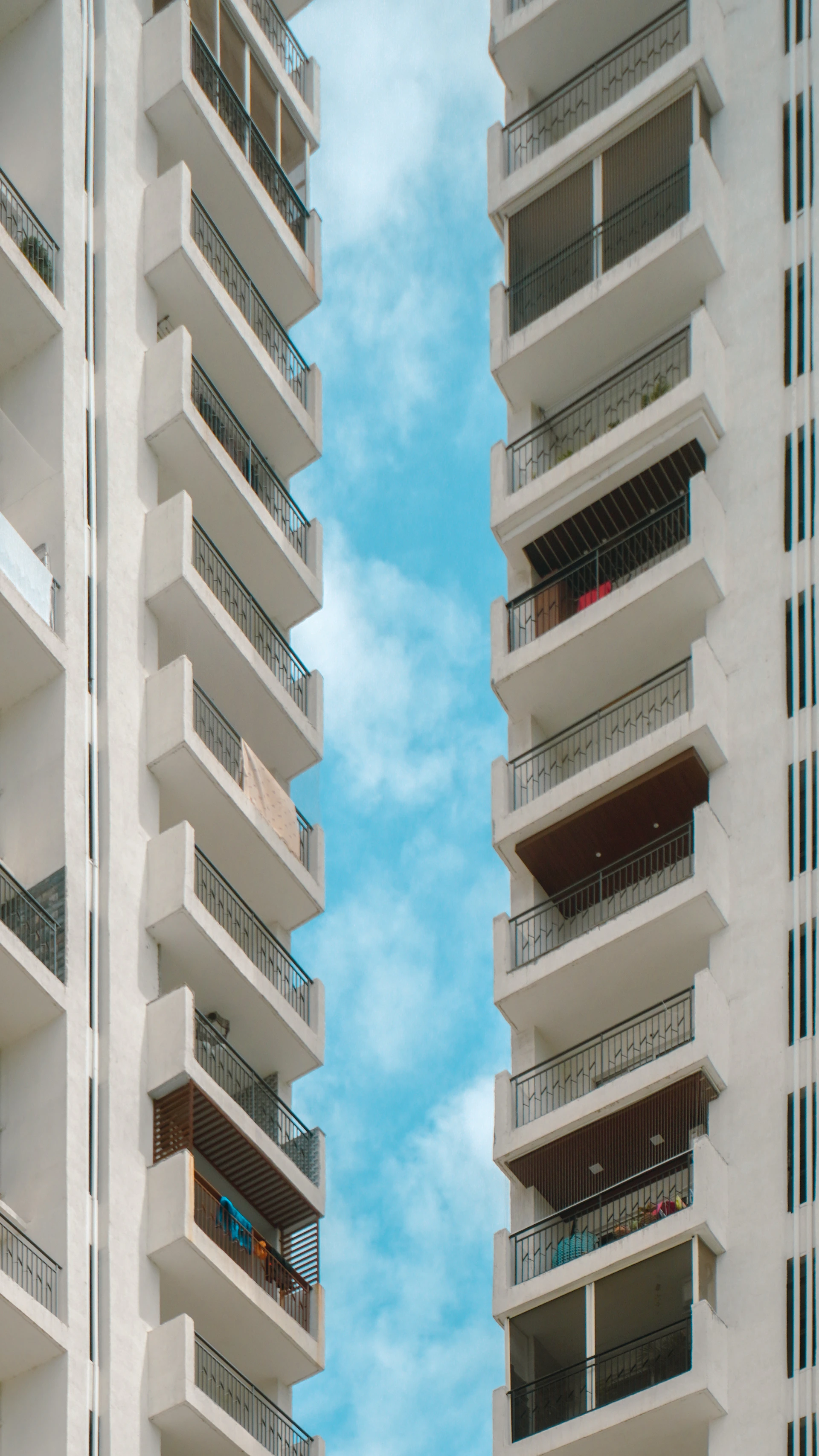 Modern apartment buildings with balconies against a bright blue sky.