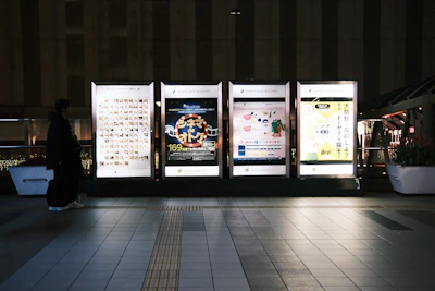 Four illuminated billboards in a city at night.