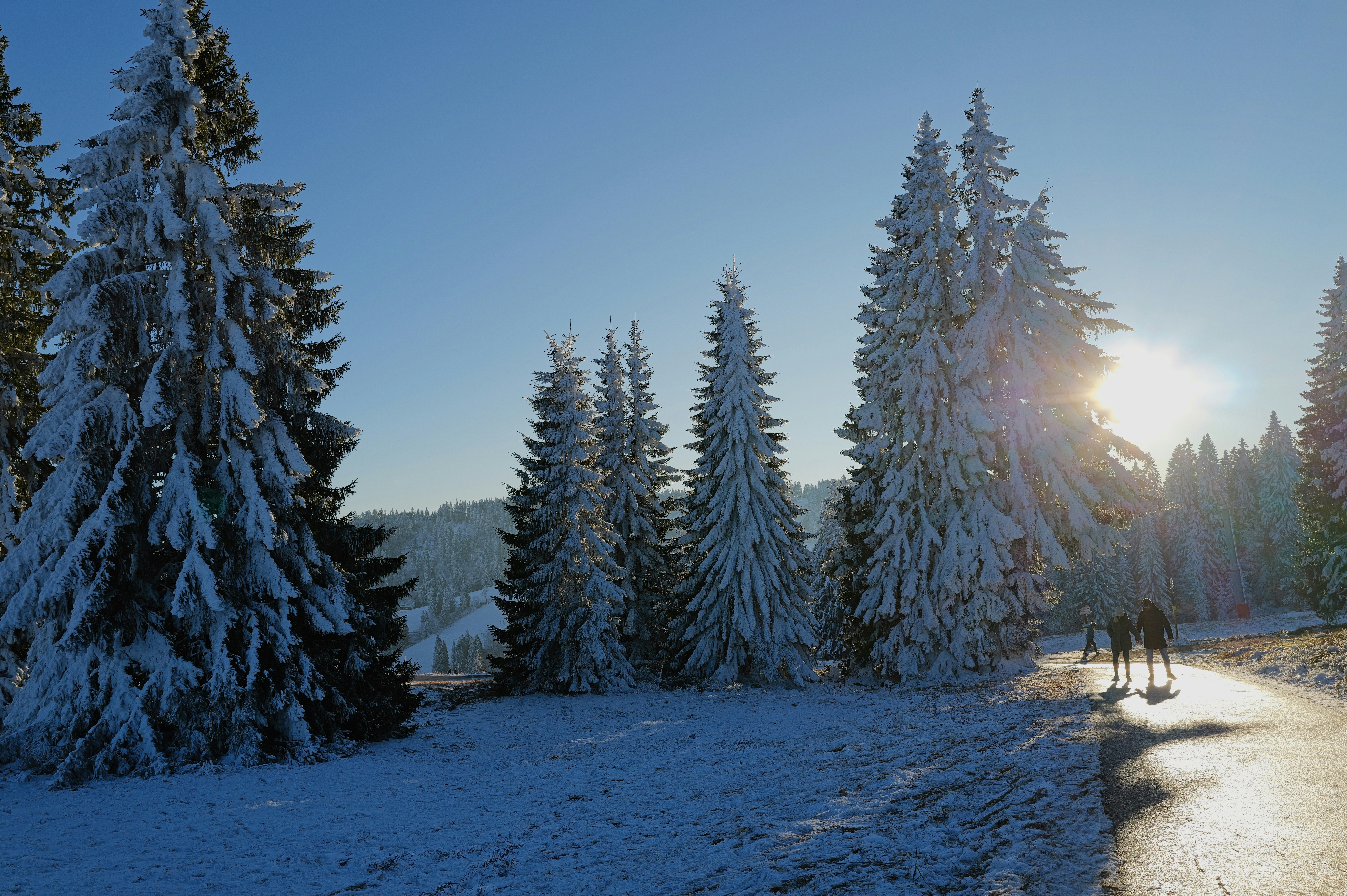 Two people cycling on a snowy path at sunset.