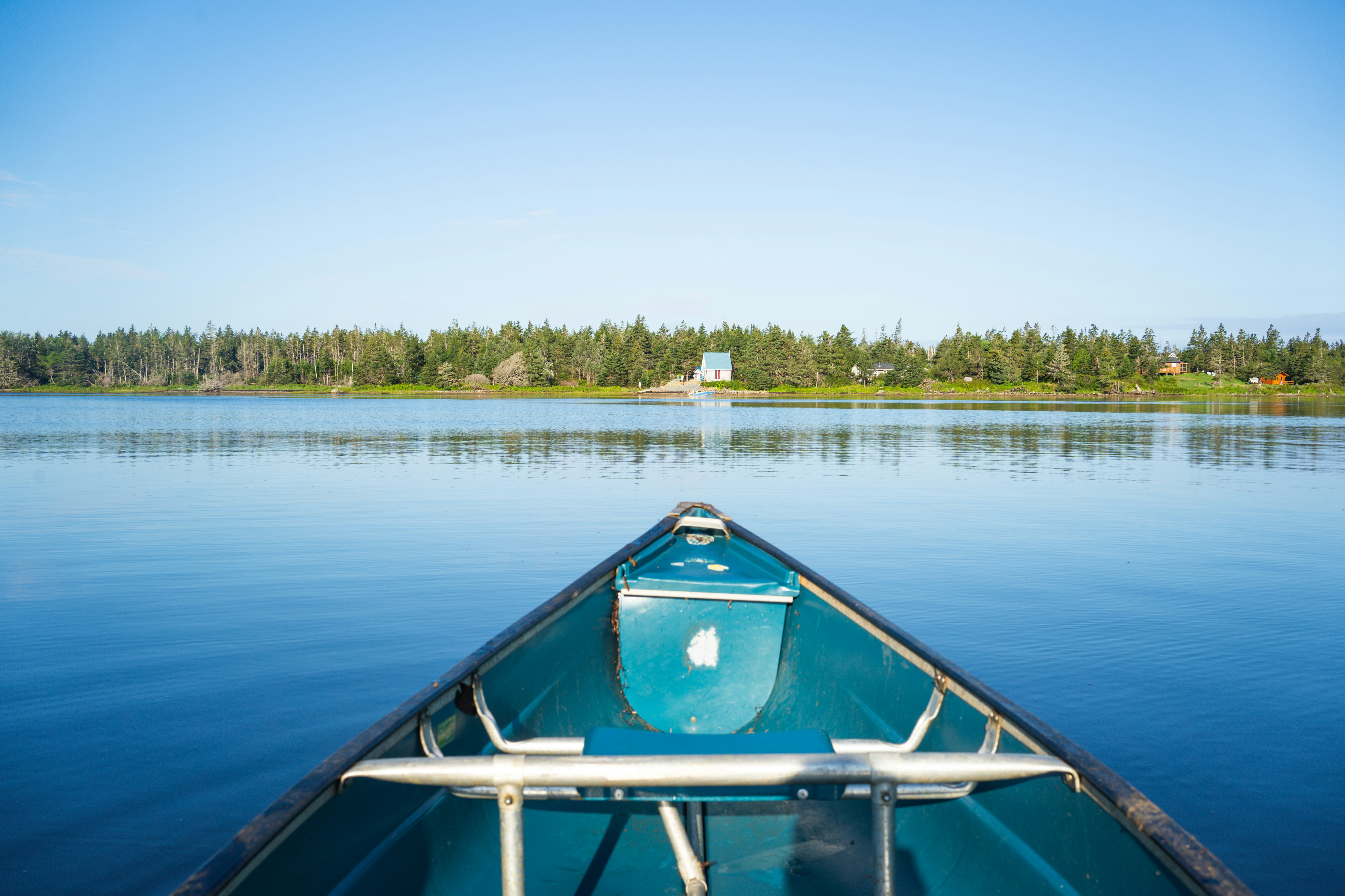 Kanu auf einem ruhigen blauen See mit entfernten Bäumen