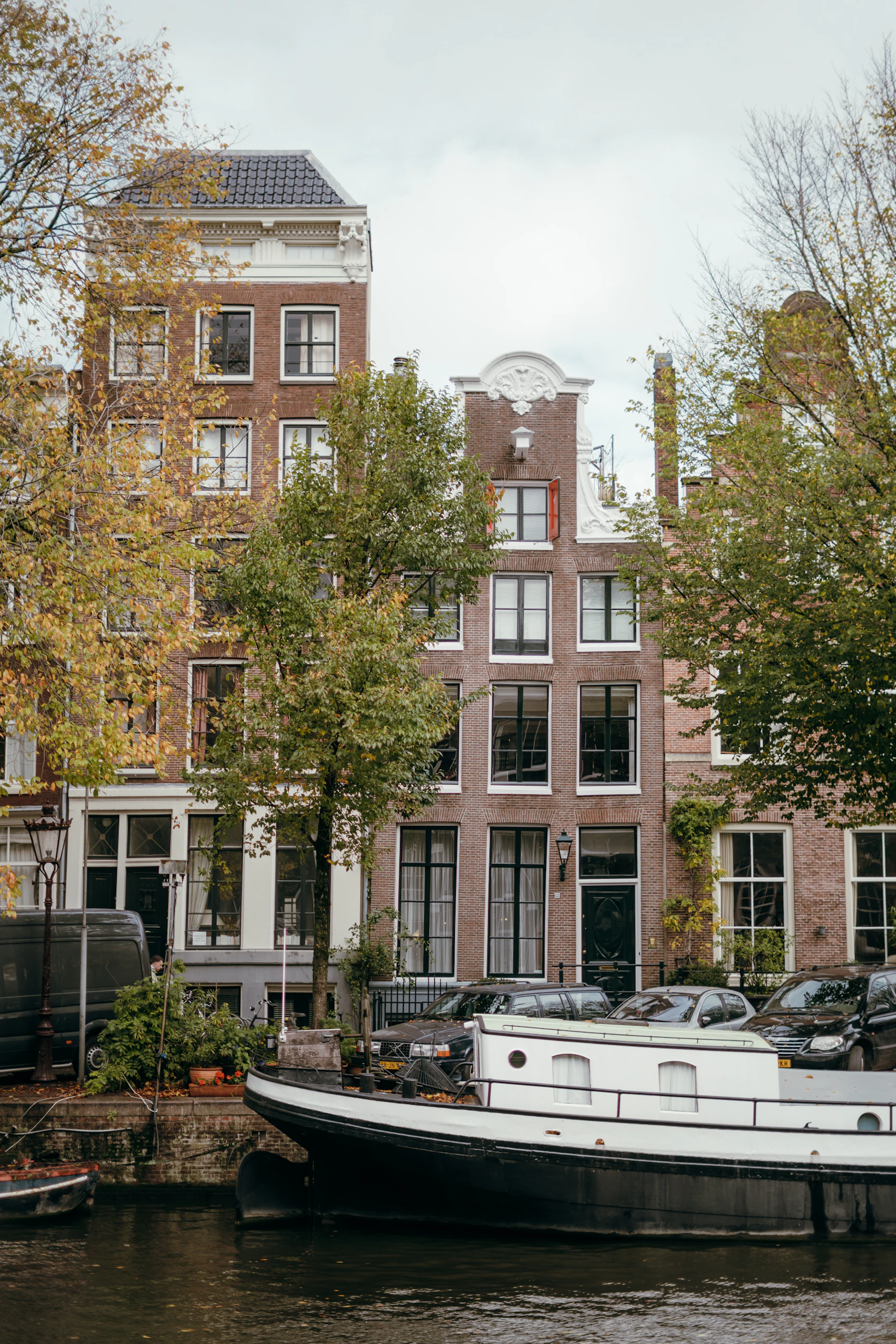 Houseboats, autumn foliage and traditional buildings along an Amsterdam canal