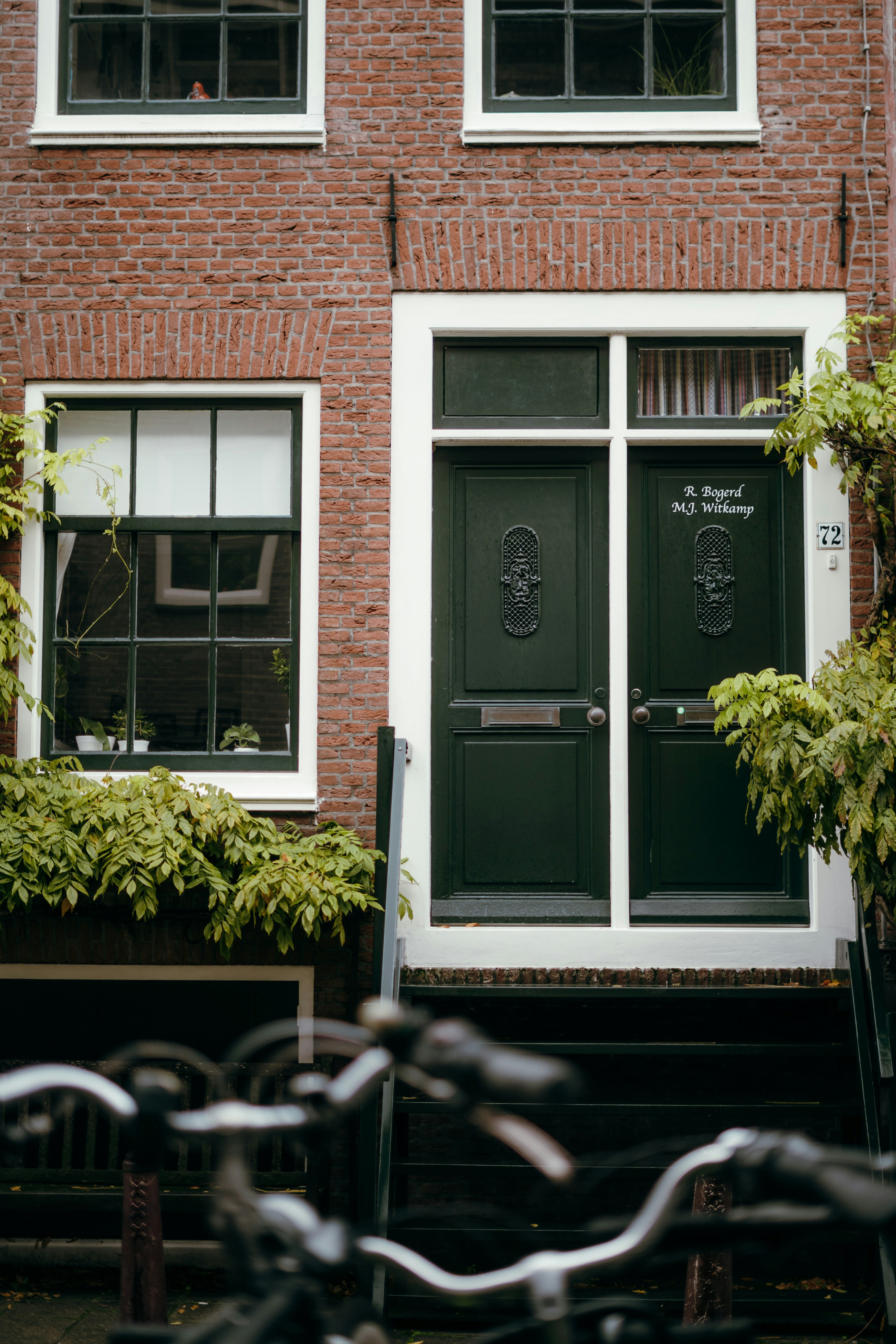 Red brick building with two green doors and windows