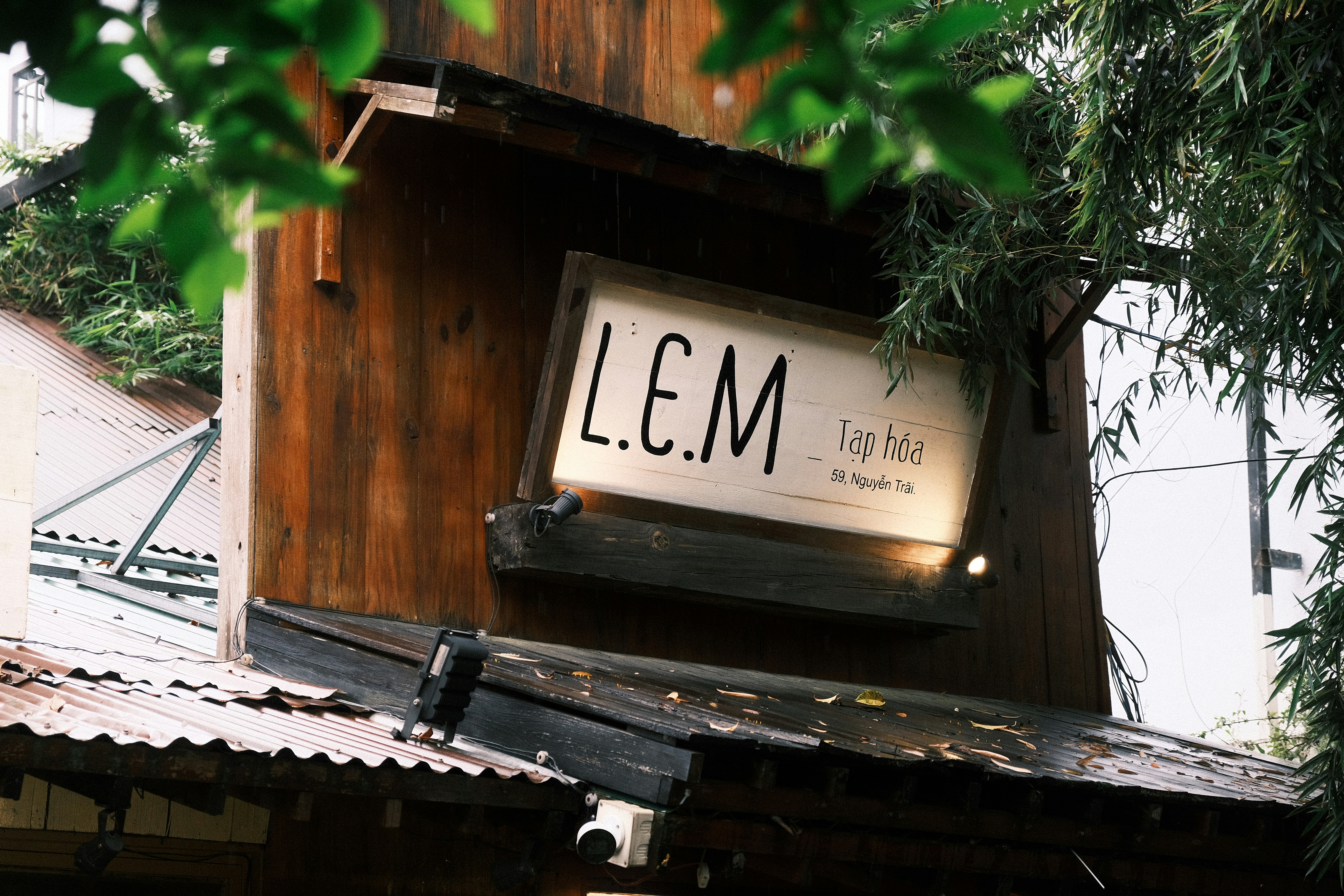 A sign for l.e.m. bar hangs on a wooden building.