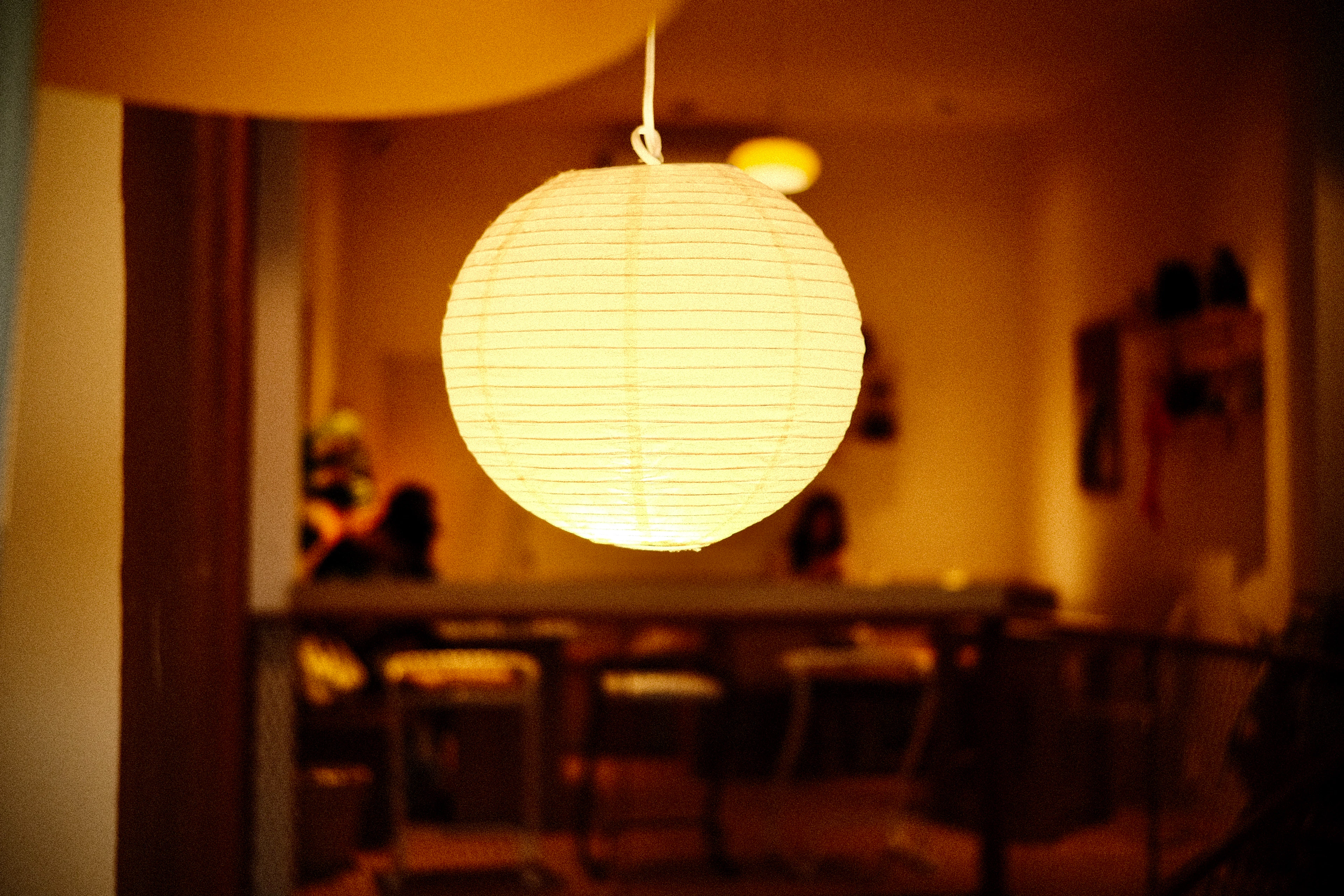 A round paper lantern glowing warmly in a dim room