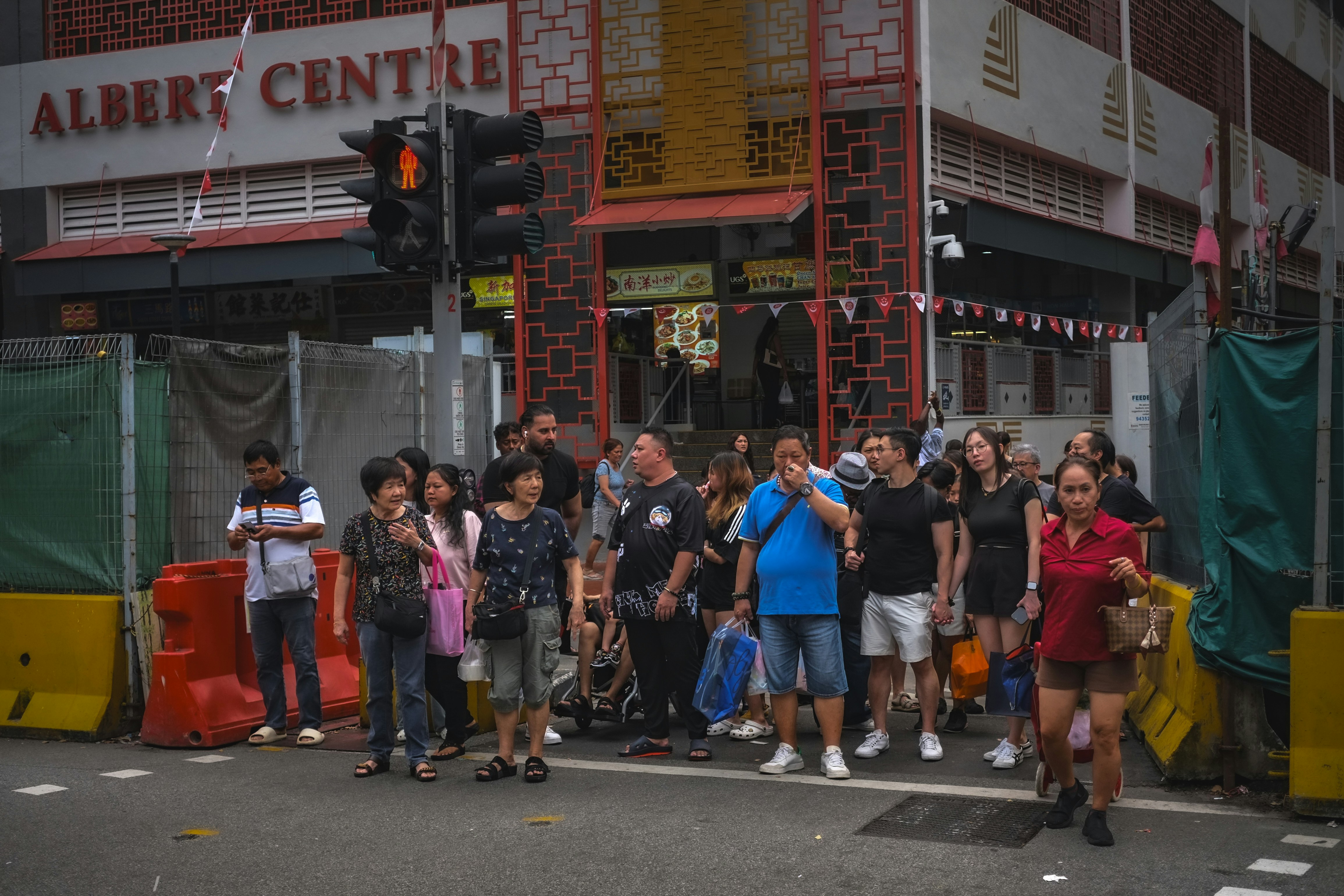 People wait at a busy city street crossing.