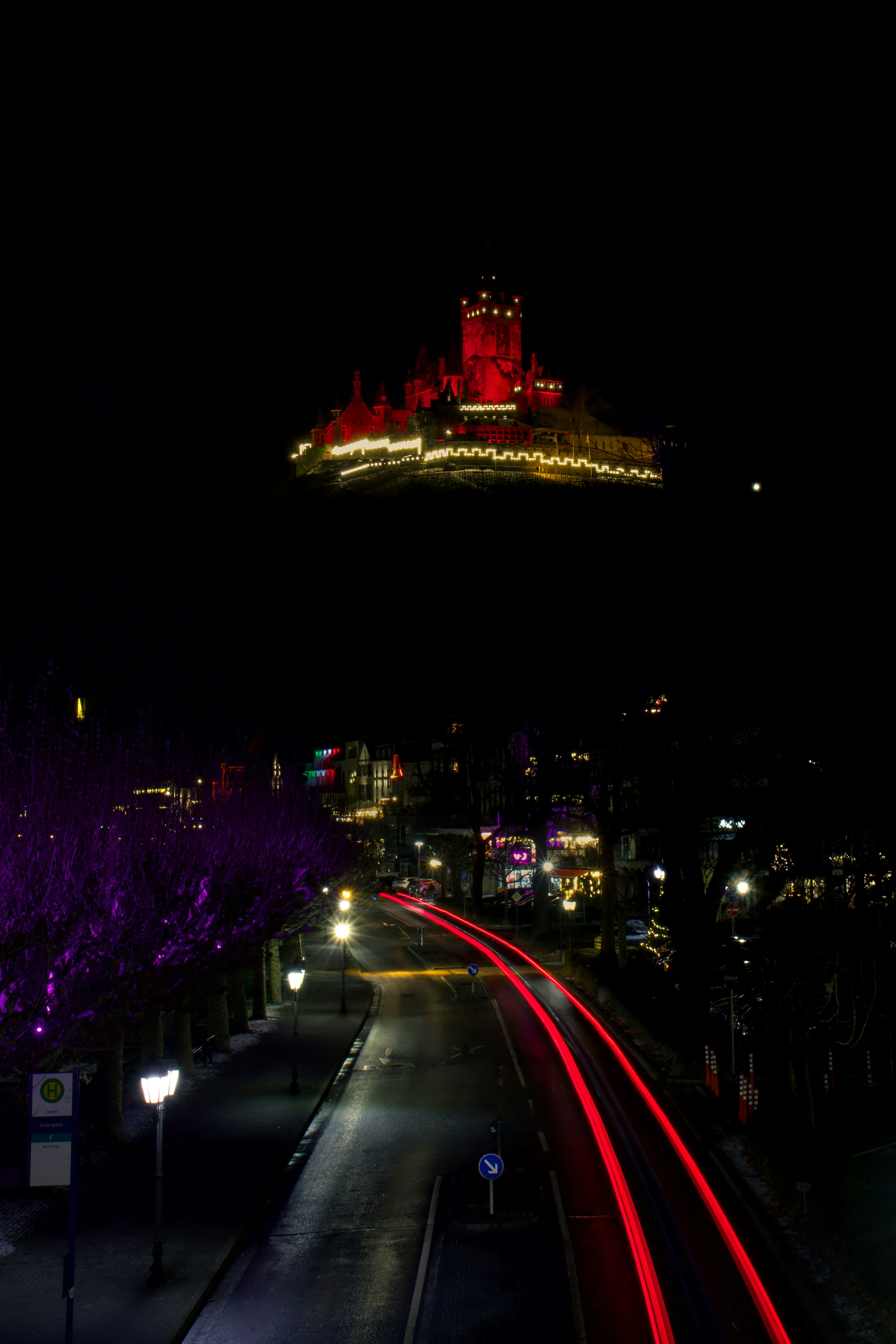 Castle illuminated red at night with light trails