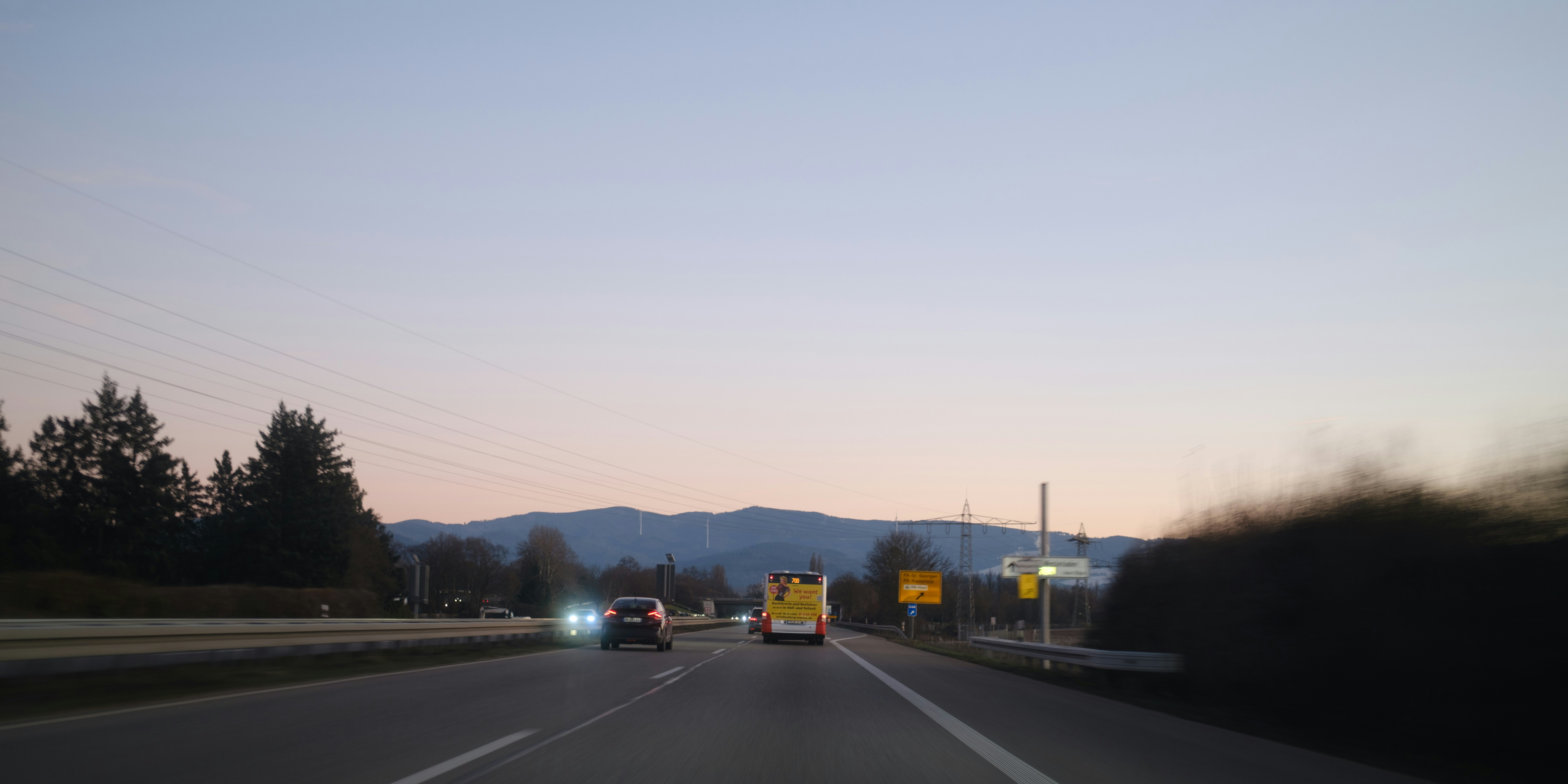 Coches en la autopista al anochecer con fondo de montañas.