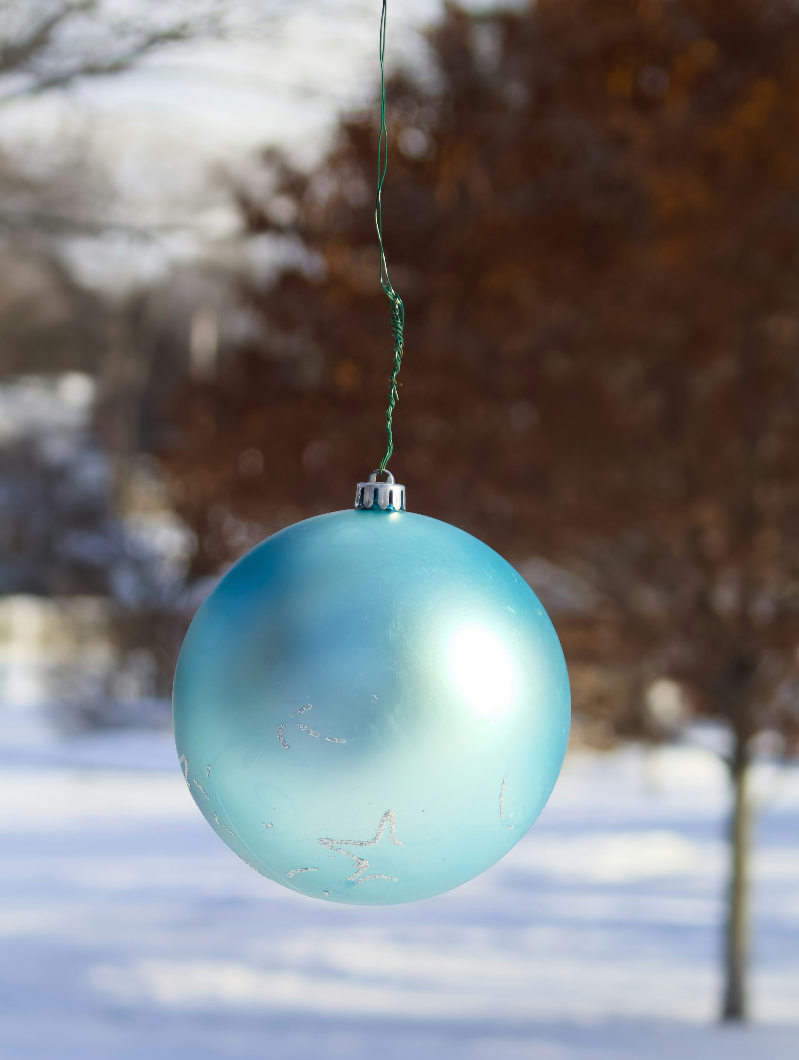 A blue ornament hangs outdoors in winter.