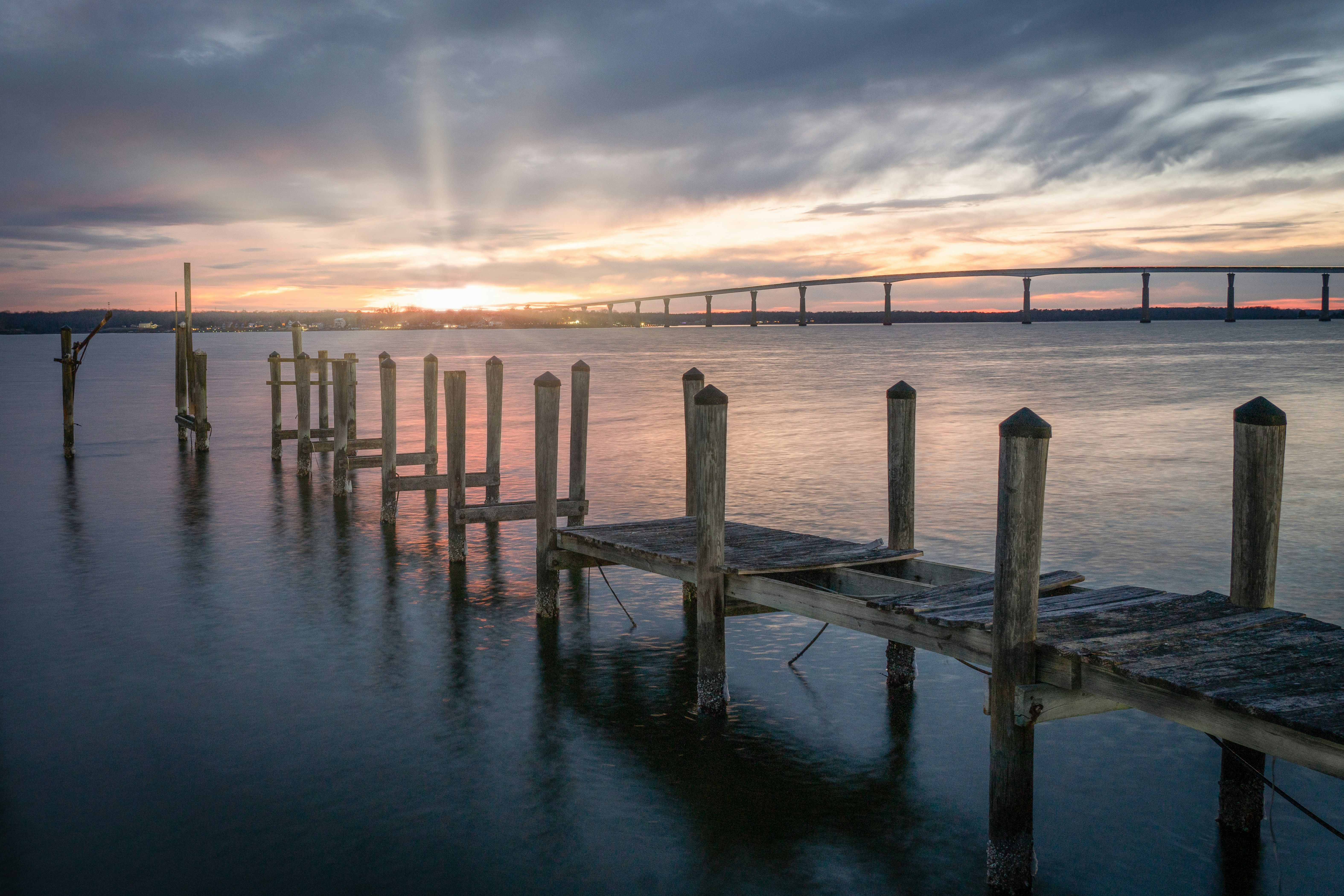Wooden pier on calm water at sunset