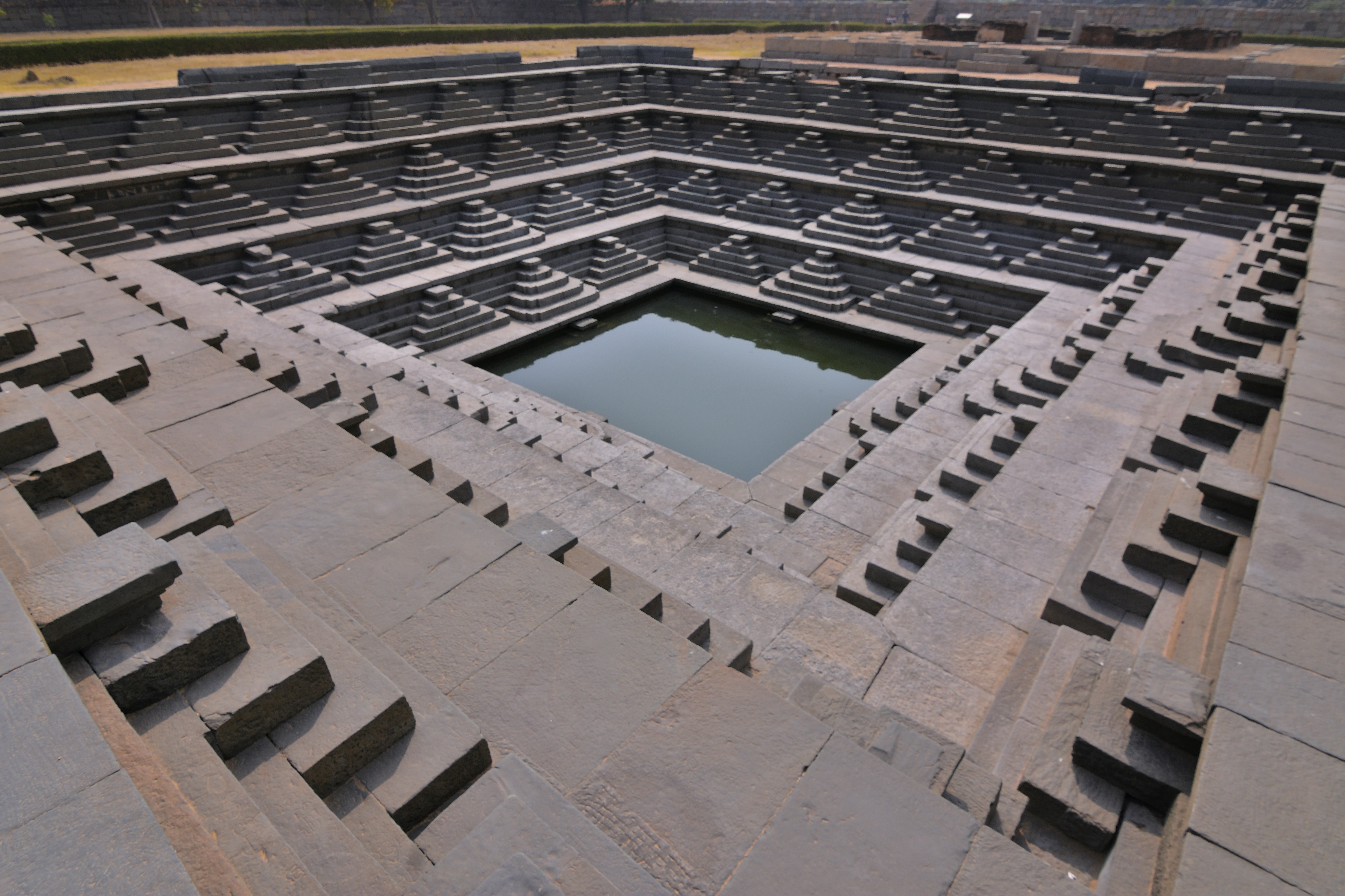 Geometric stepped well with water in the center.