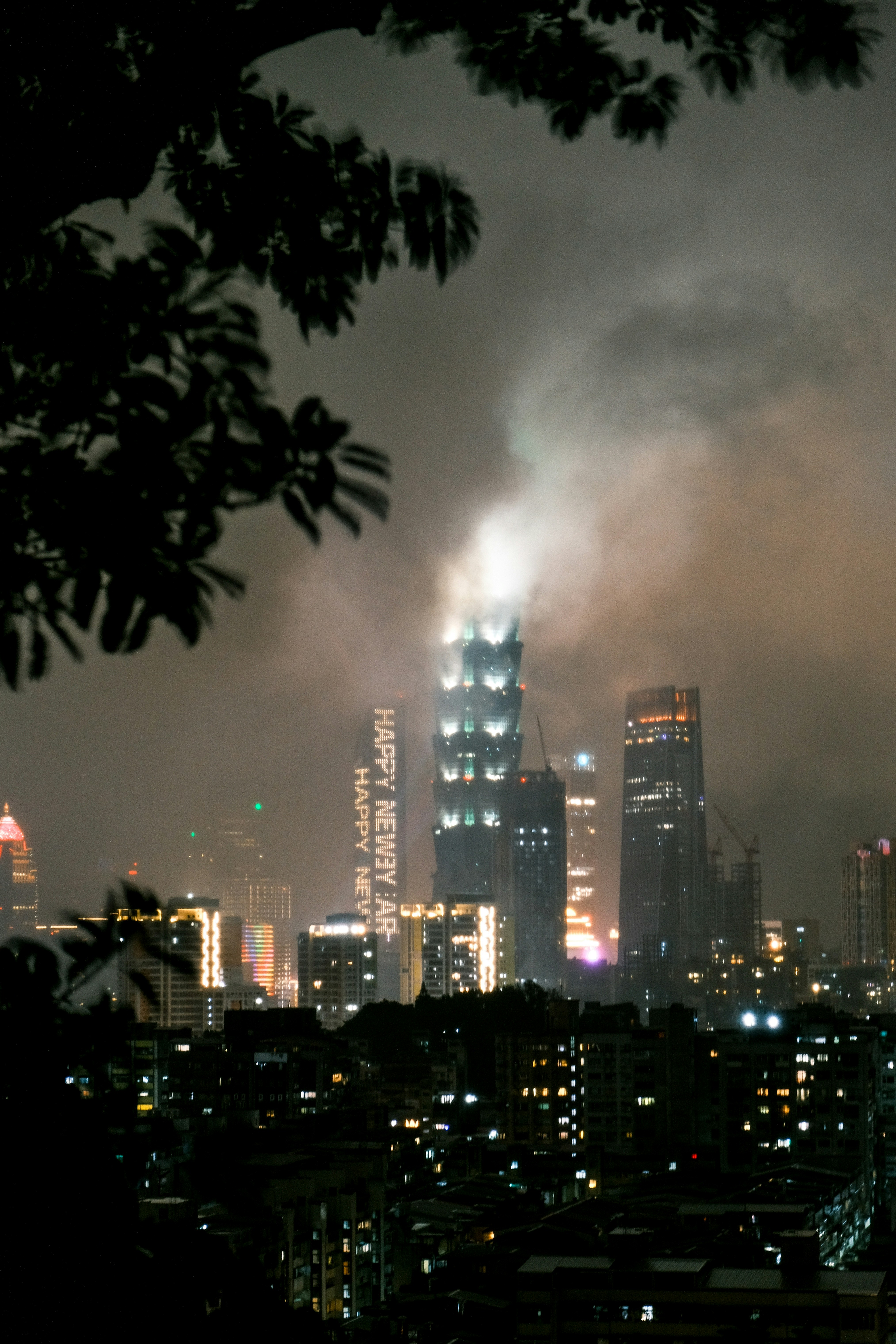 Horizonte da cidade à noite, com arranha-céus iluminados e fumaça.