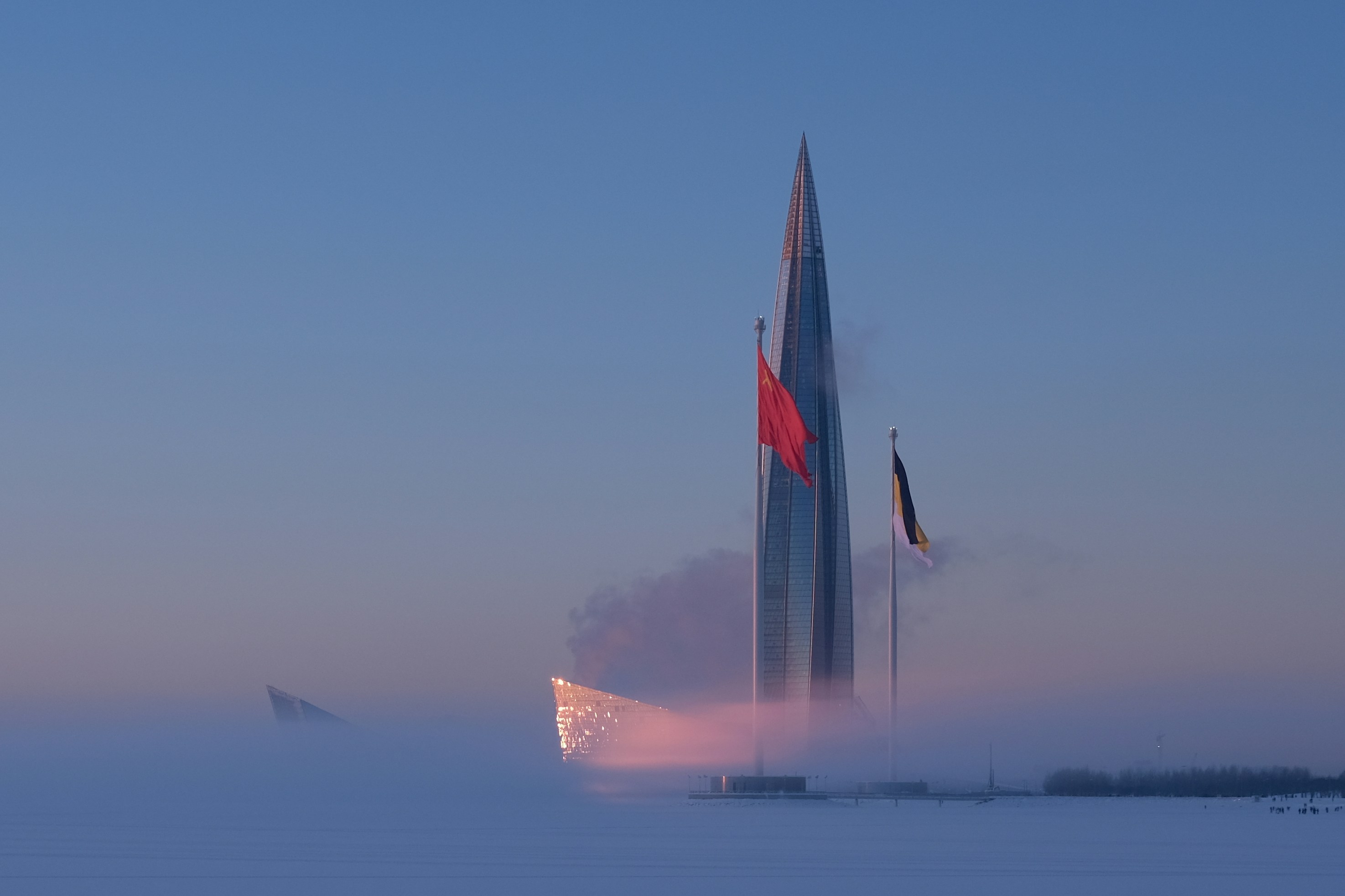Modern skyscraper emerging from mist at sunrise