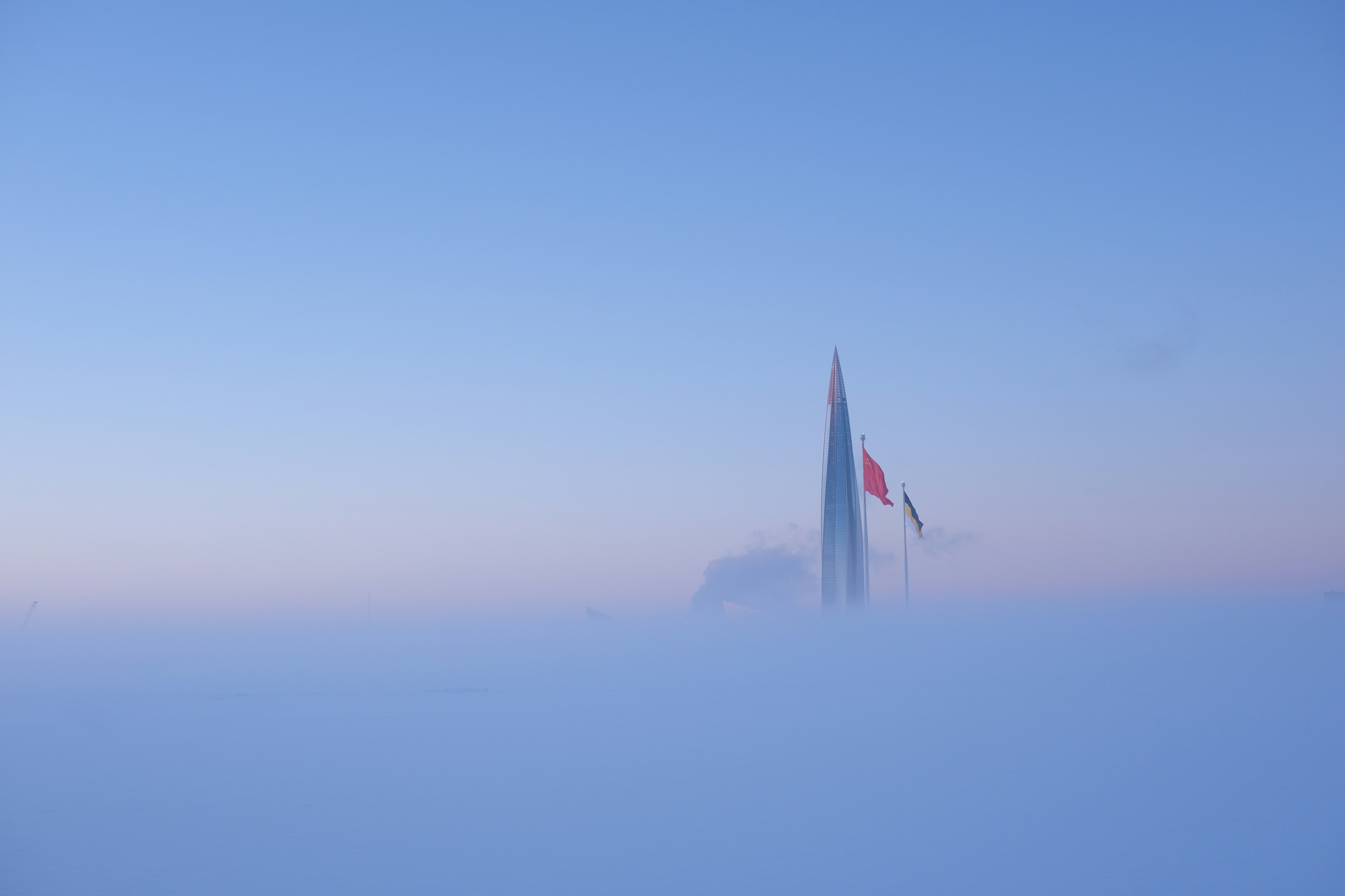 Skyscraper emerging from thick fog at dawn.