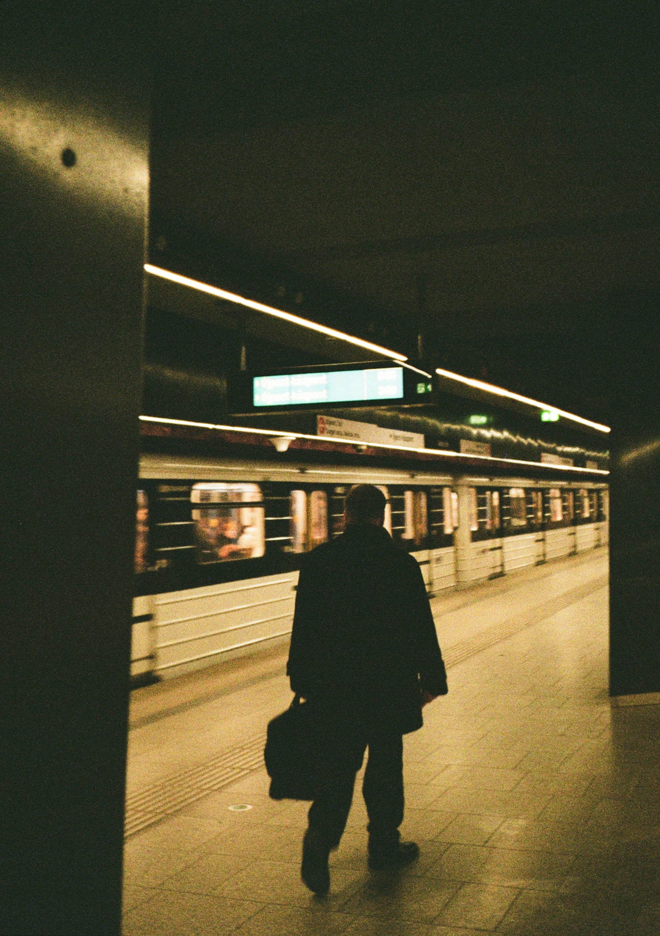 Man walking on subway platform towards train.