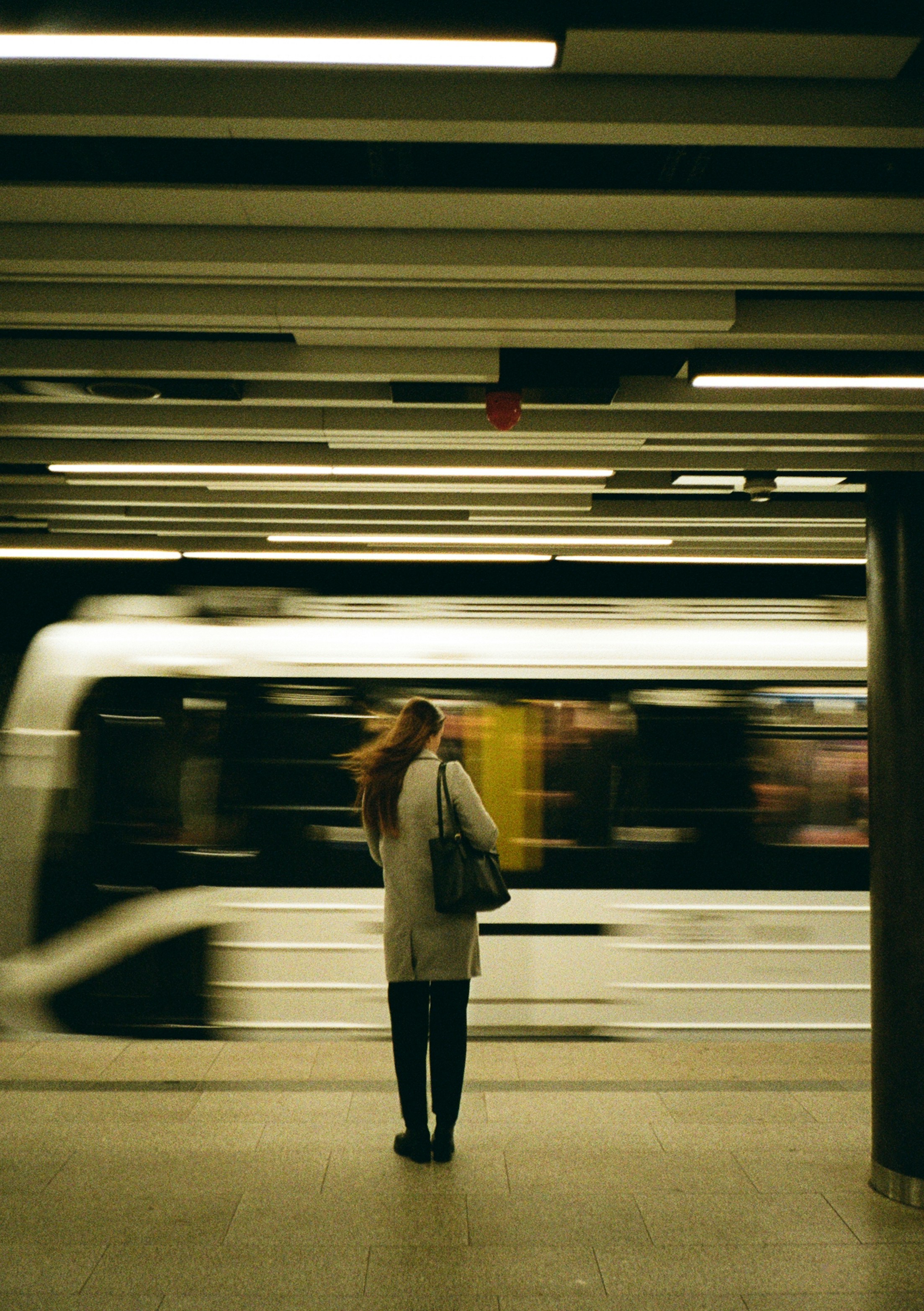 Woman waits for train in blurred station