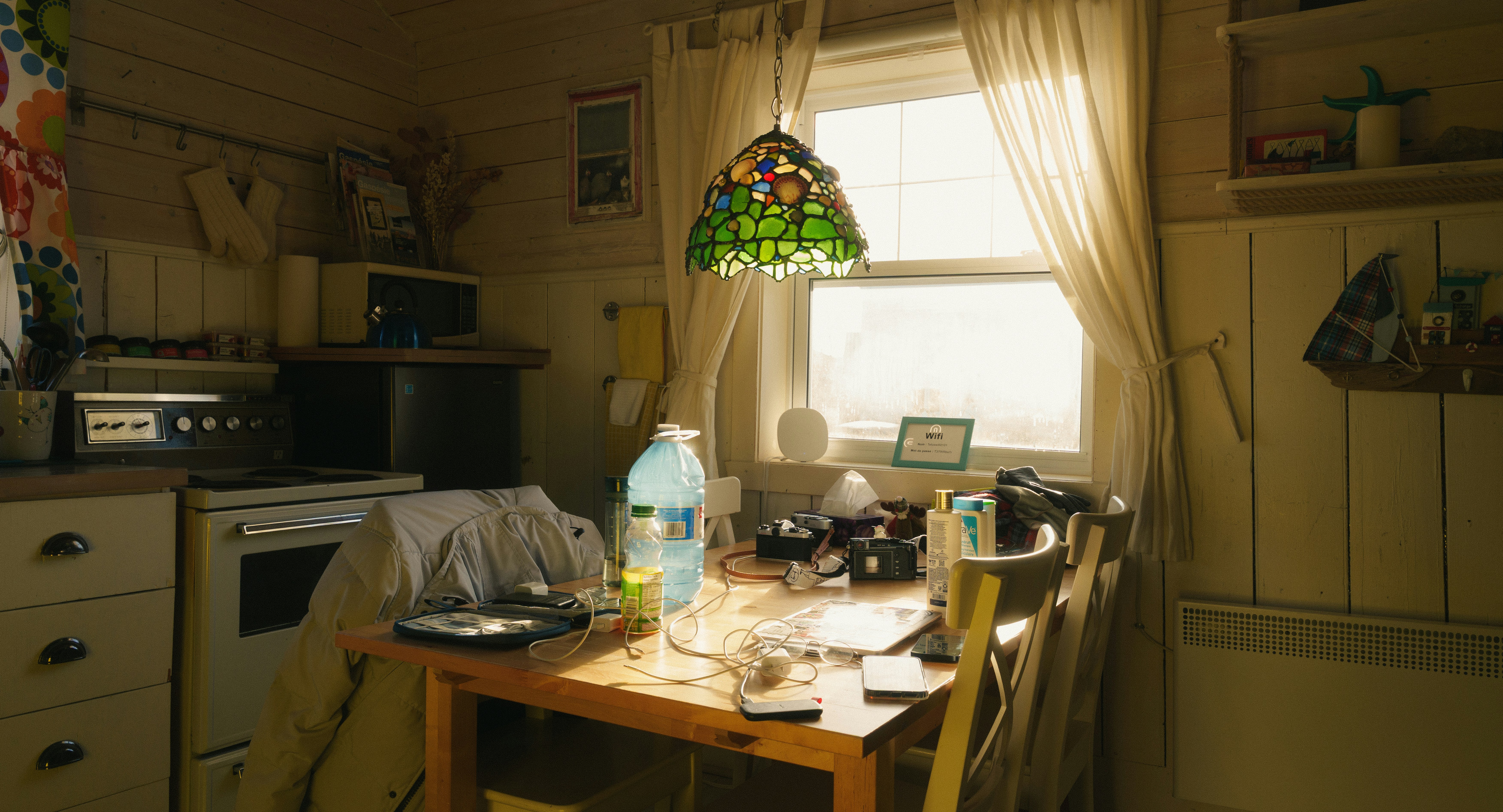 A cluttered kitchen table with a window