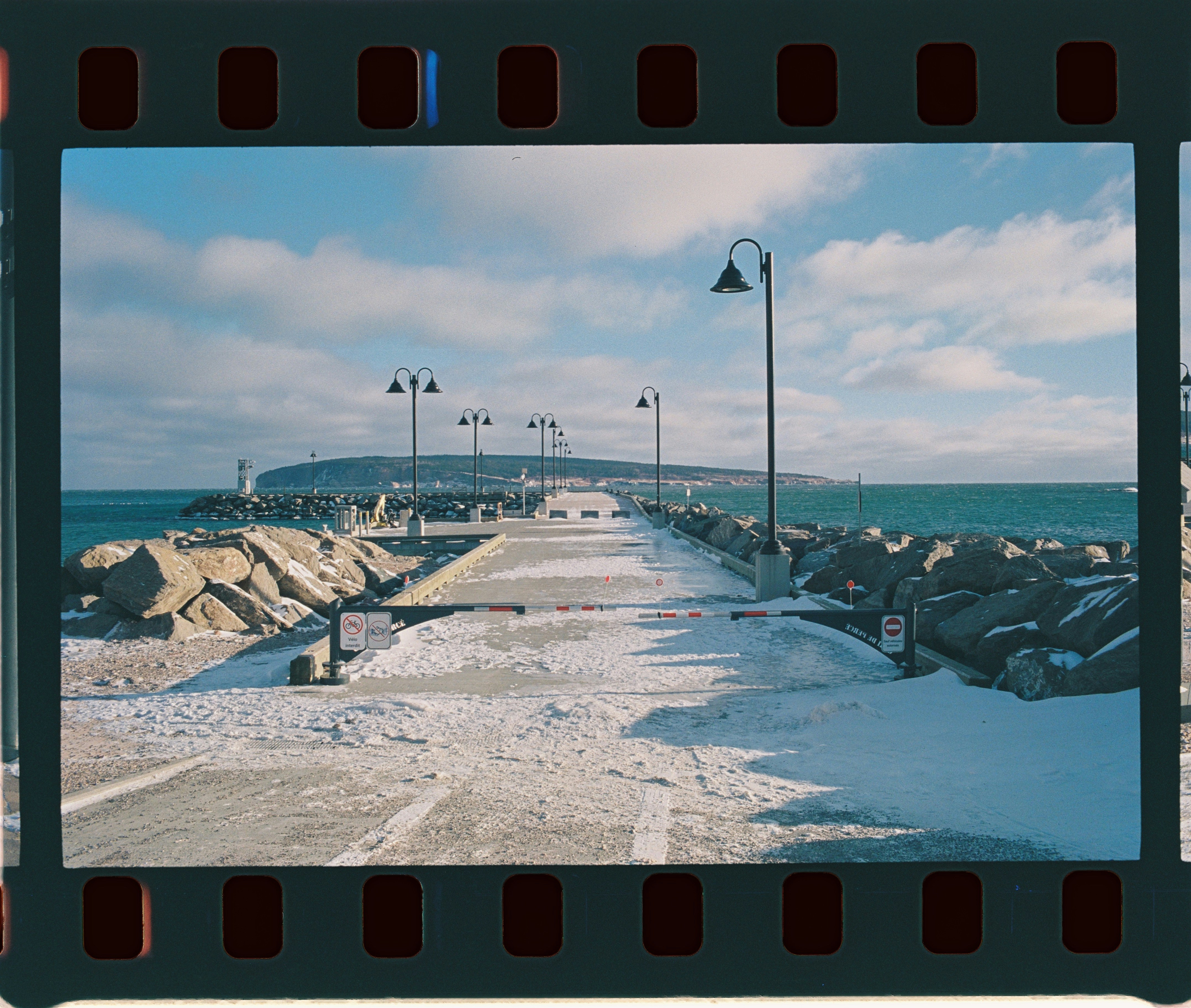 Snowy pier with ocean and distant island