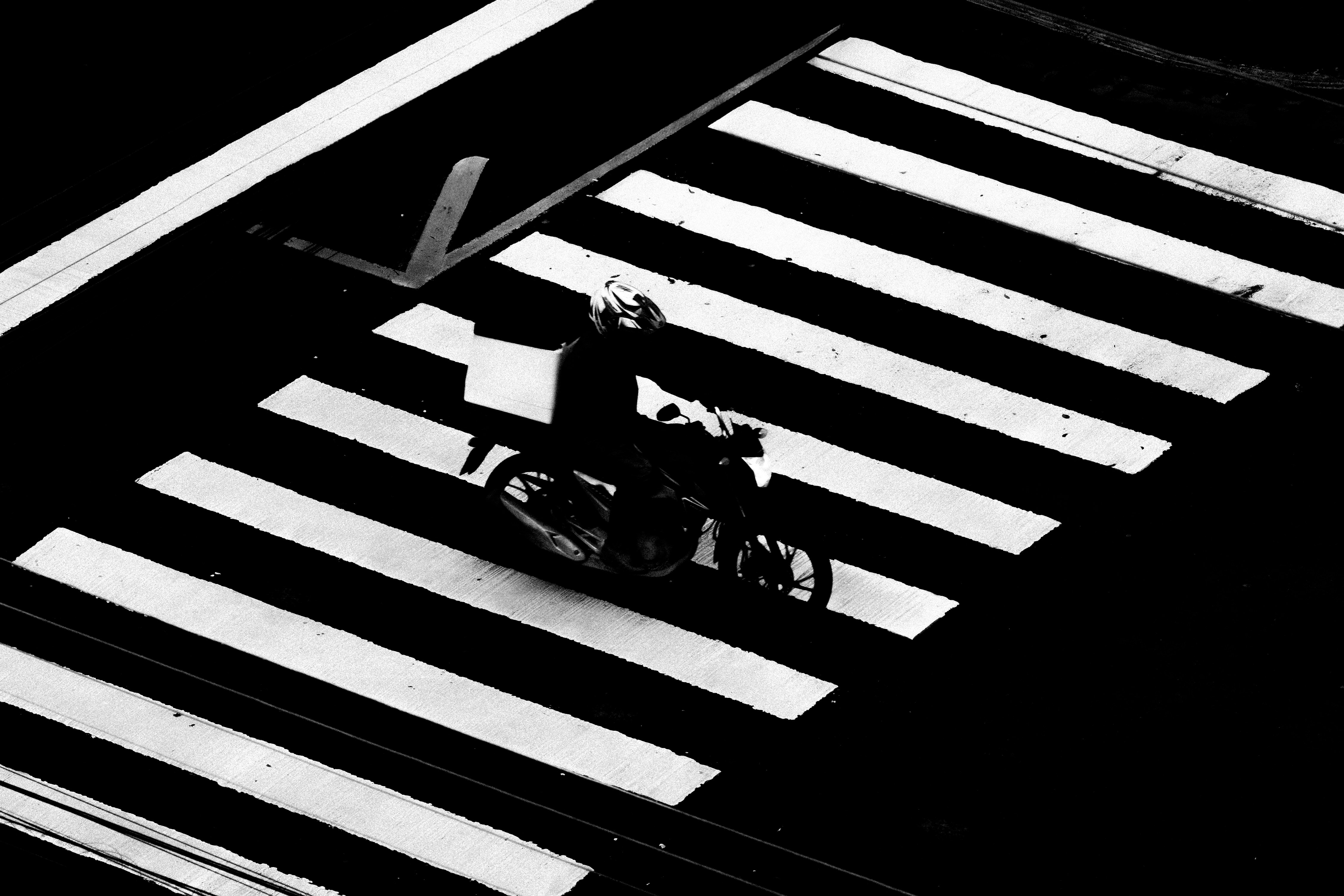 Motorcyclist crossing a black and white zebra crossing.