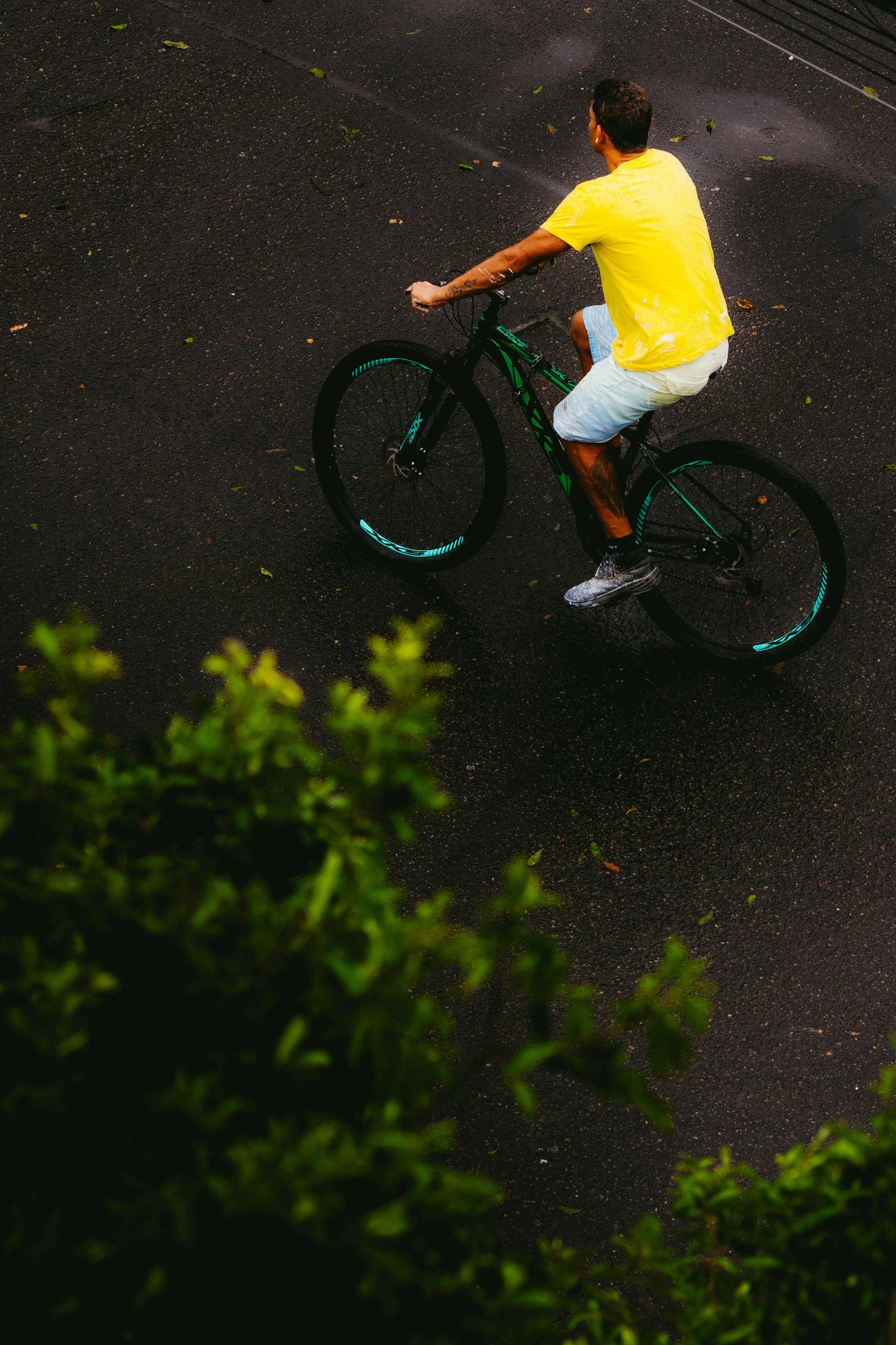 Man in yellow shirt rides bicycle on wet road