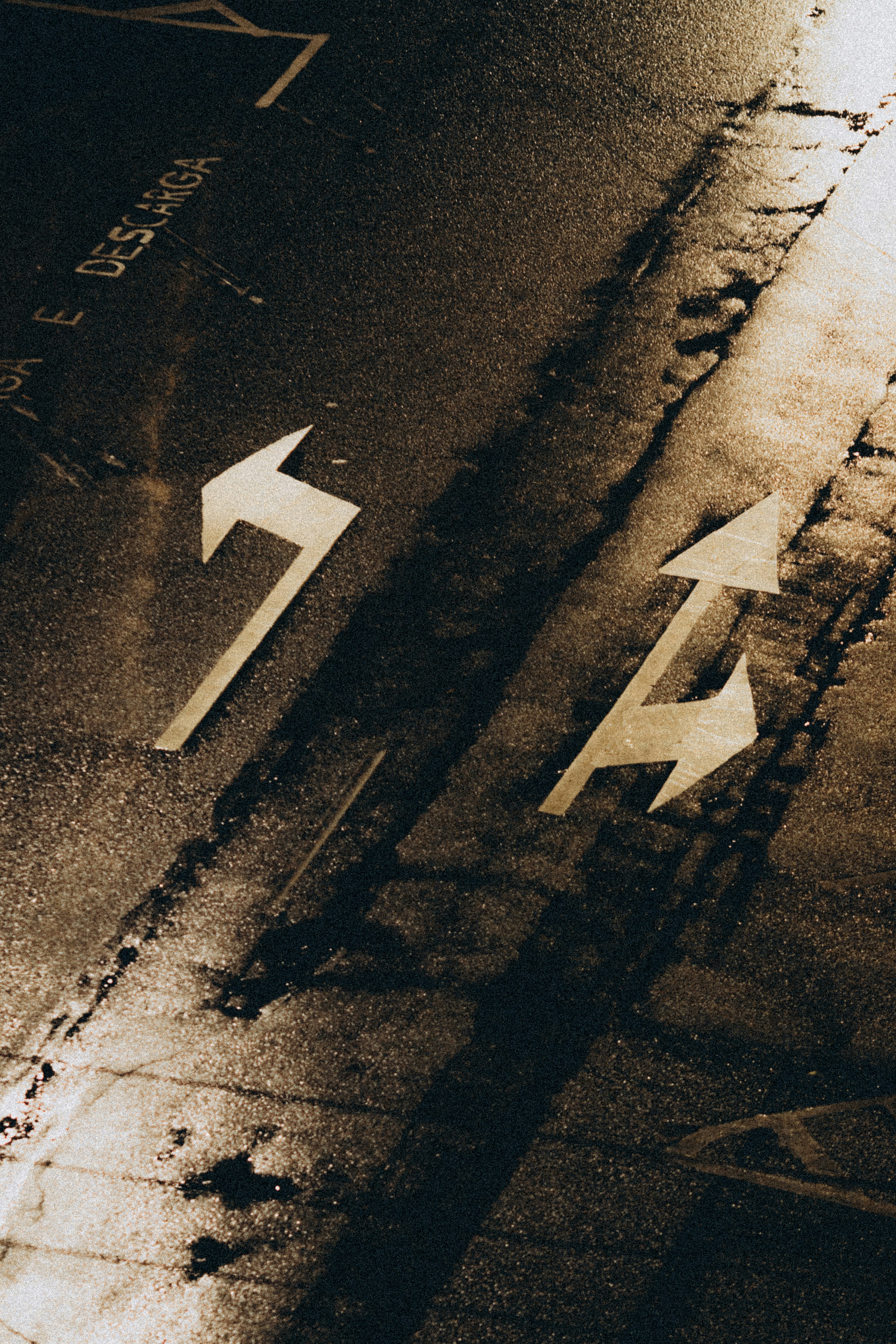 Two arrows painted on a wet asphalt road.