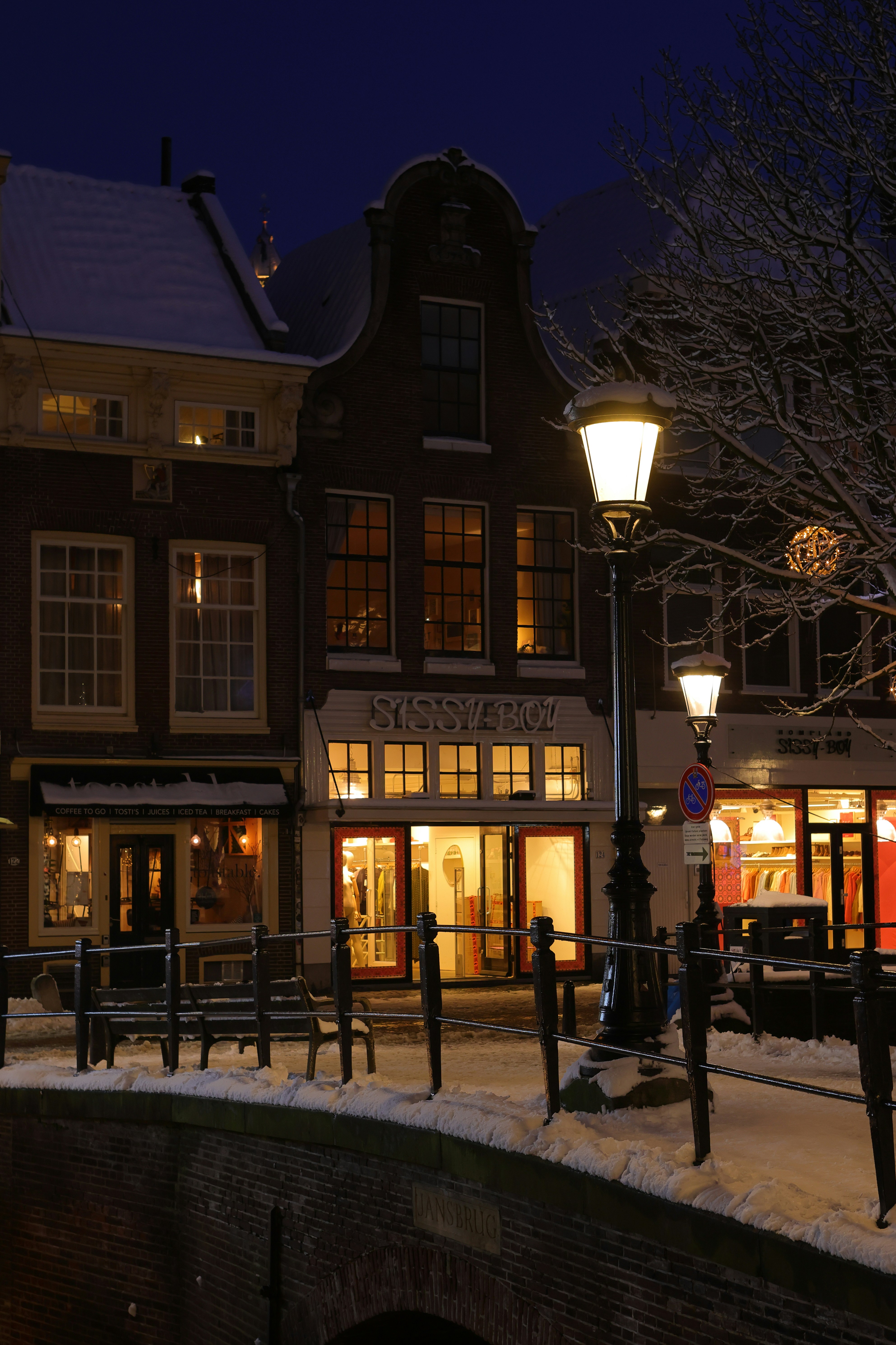 Rua nevada com lojas iluminadas à noite