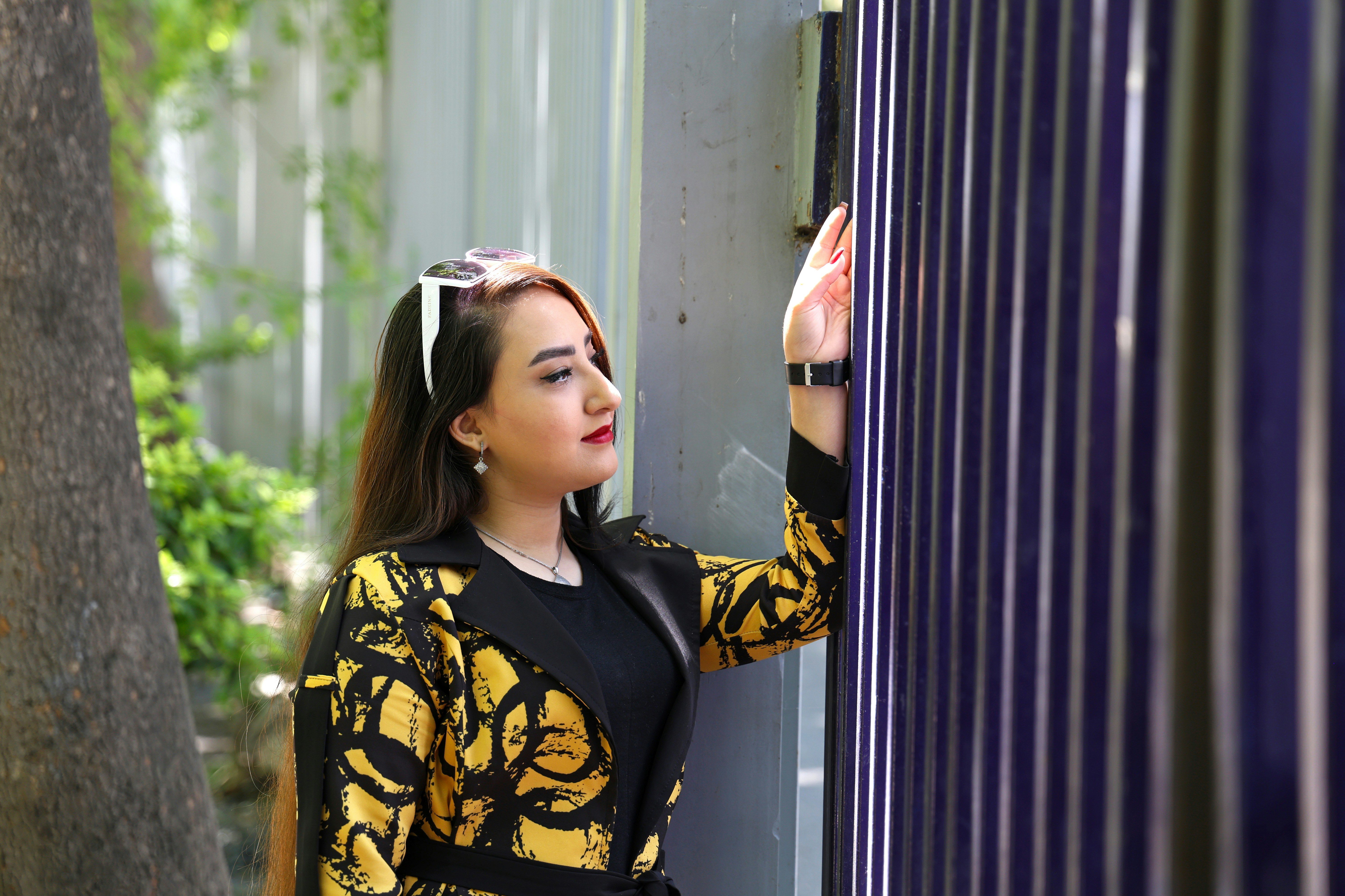 A woman in a patterned jacket looking at a fence