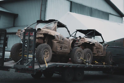 Two damaged off-road vehicles on a flatbed trailer.