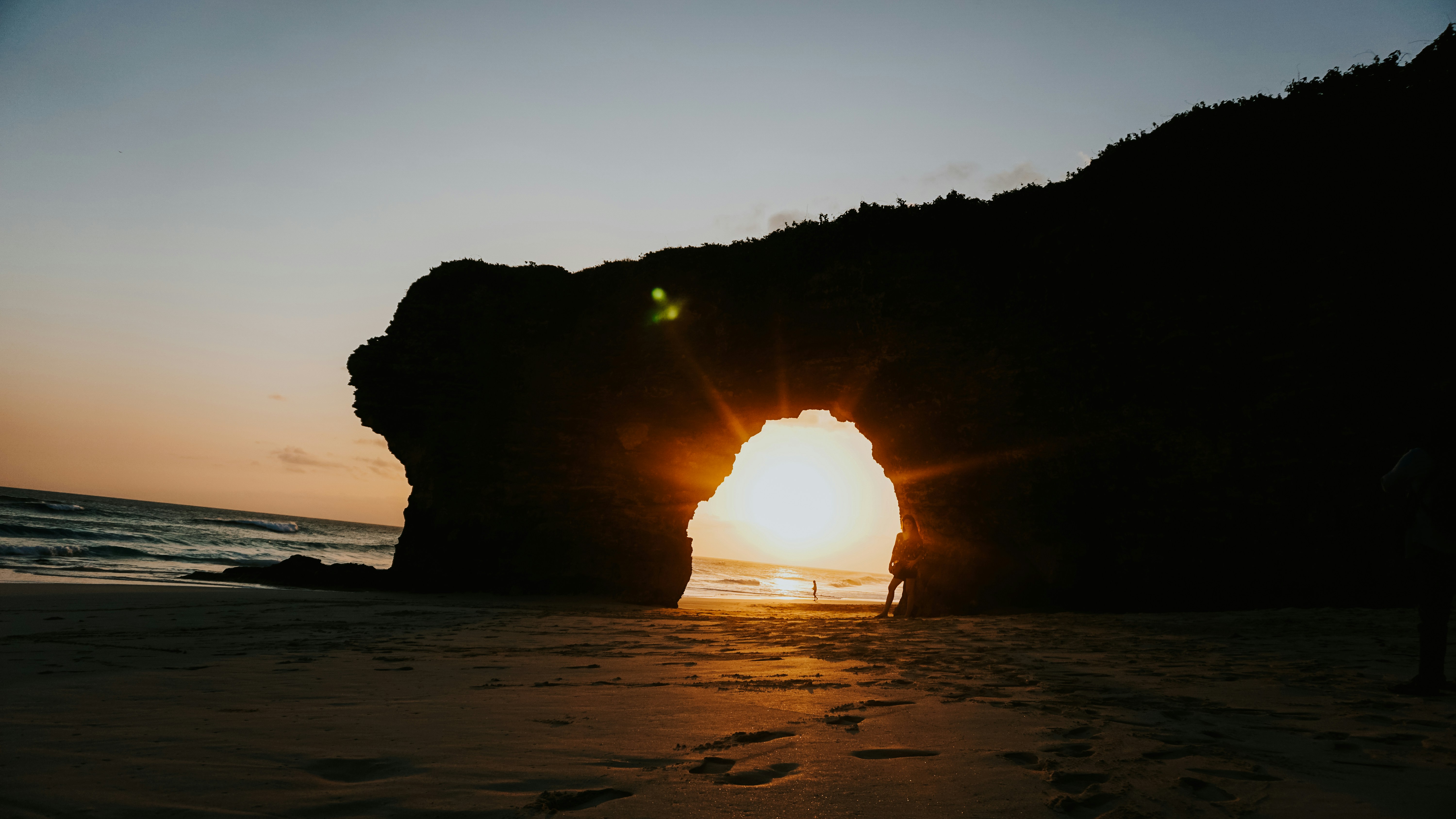 Sunset through a natural rock archway on beach