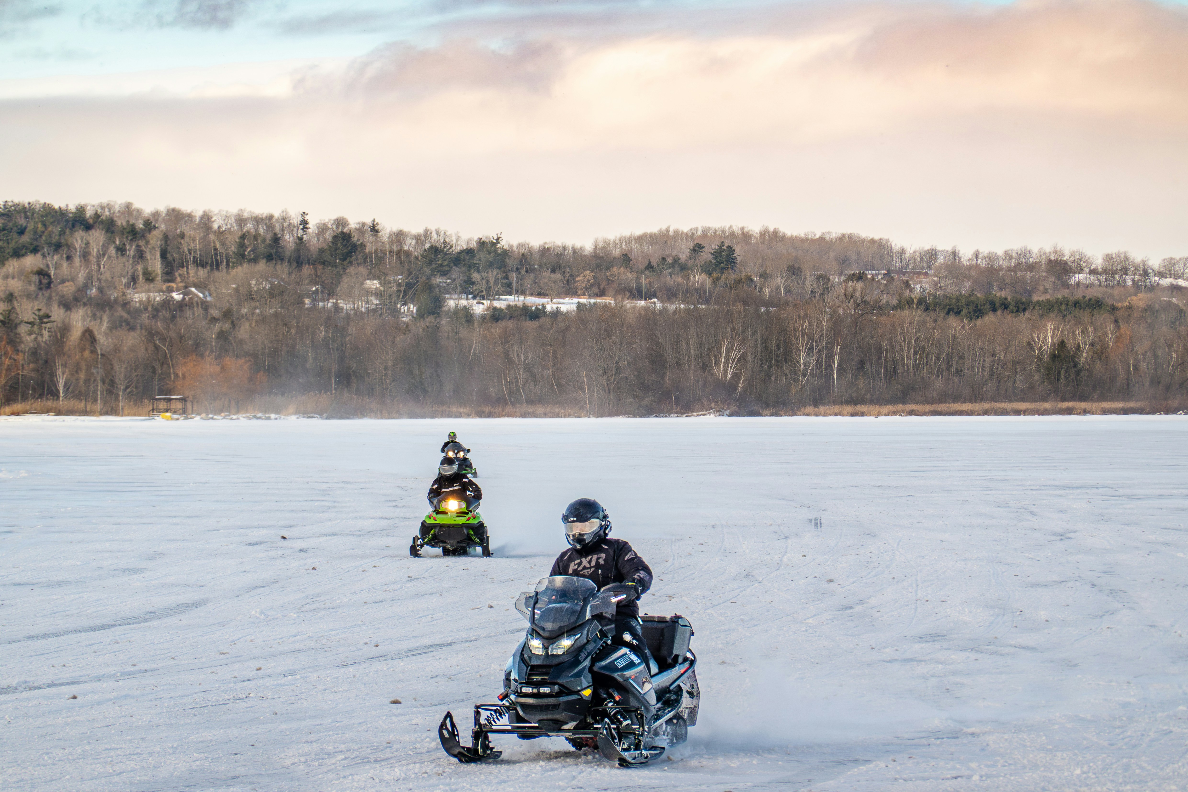 Two people snowmobiling across a frozen landscape.