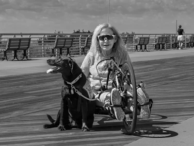 Woman in handcycle with service dog on boardwalk