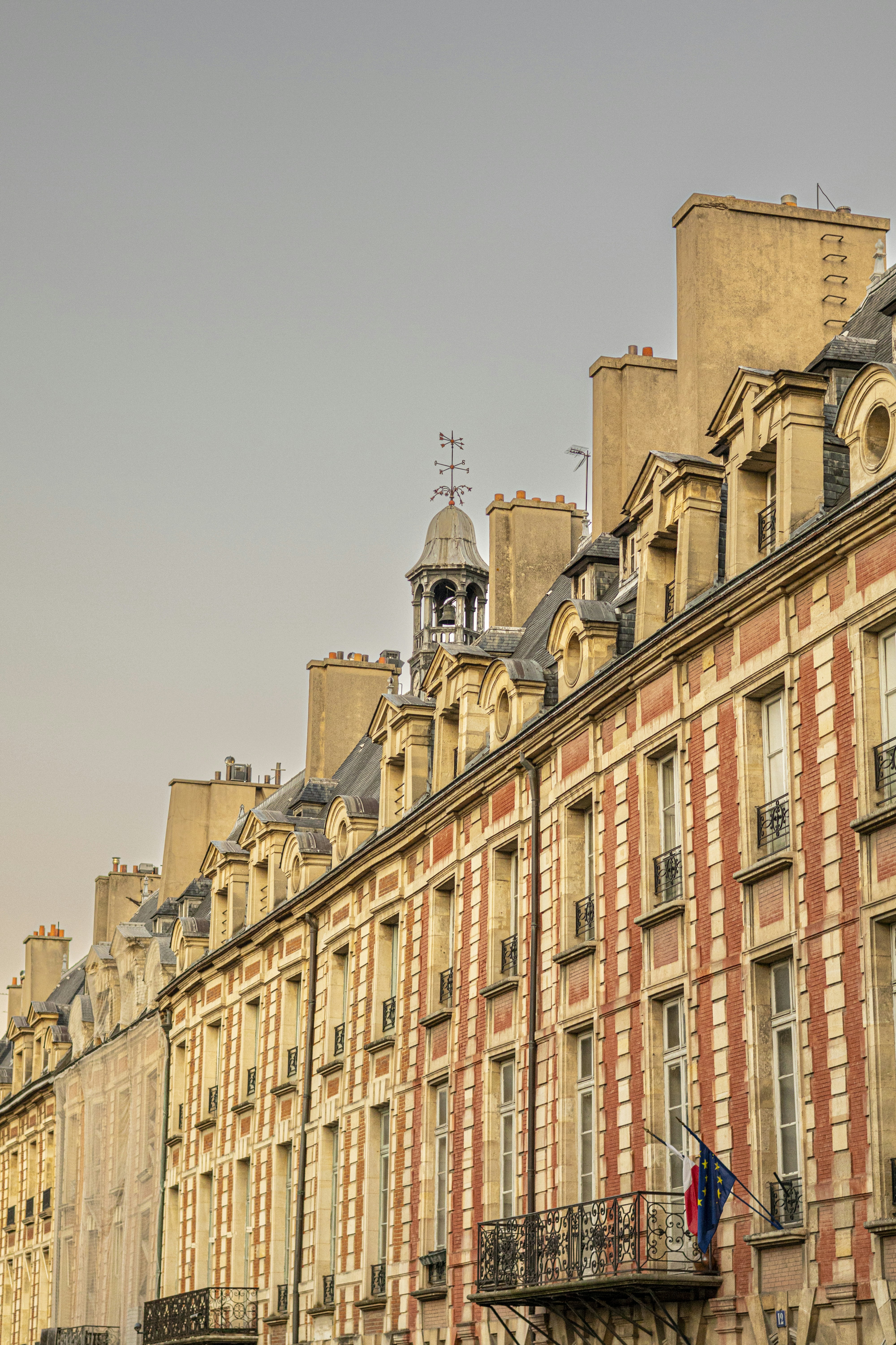 Row of historic buildings with dormer windows and chimneys.