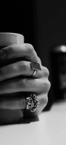 Close-up of hands holding a mug with rings.