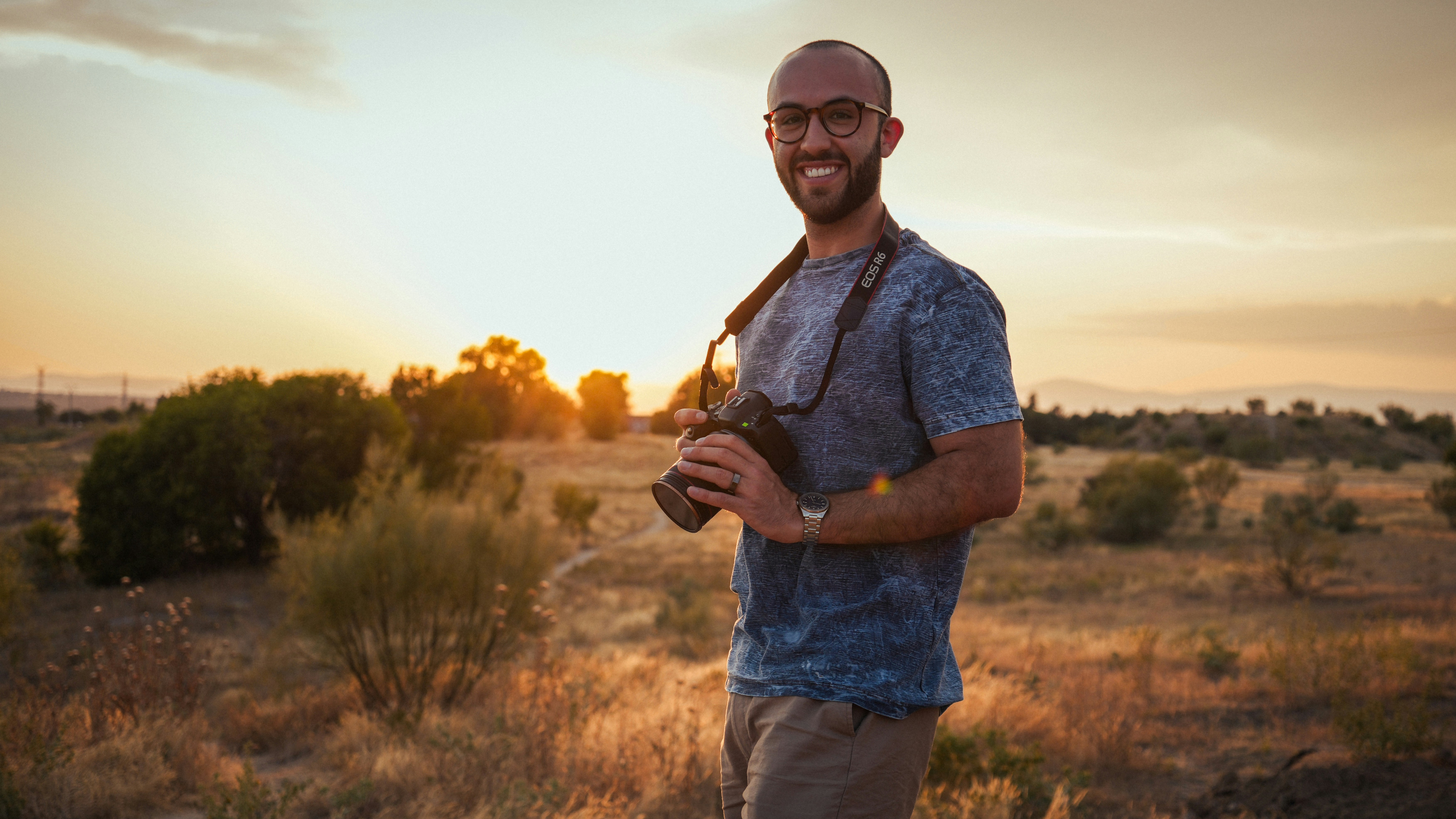 Mann mit Kamera bei Sonnenuntergang auf einem Feld