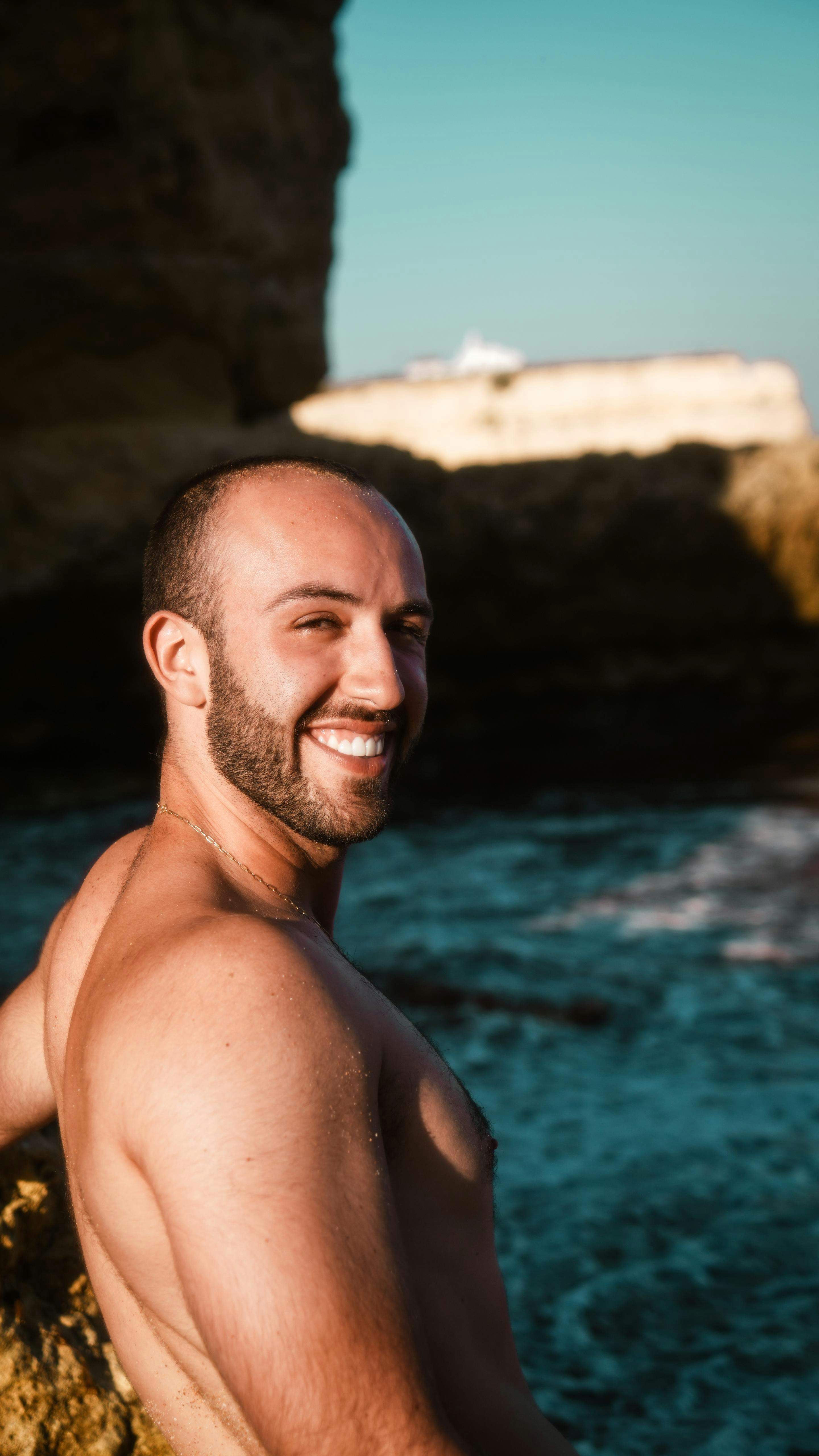 Mann lächelt an einem felsigen Strand mit Wellen des Ozeans