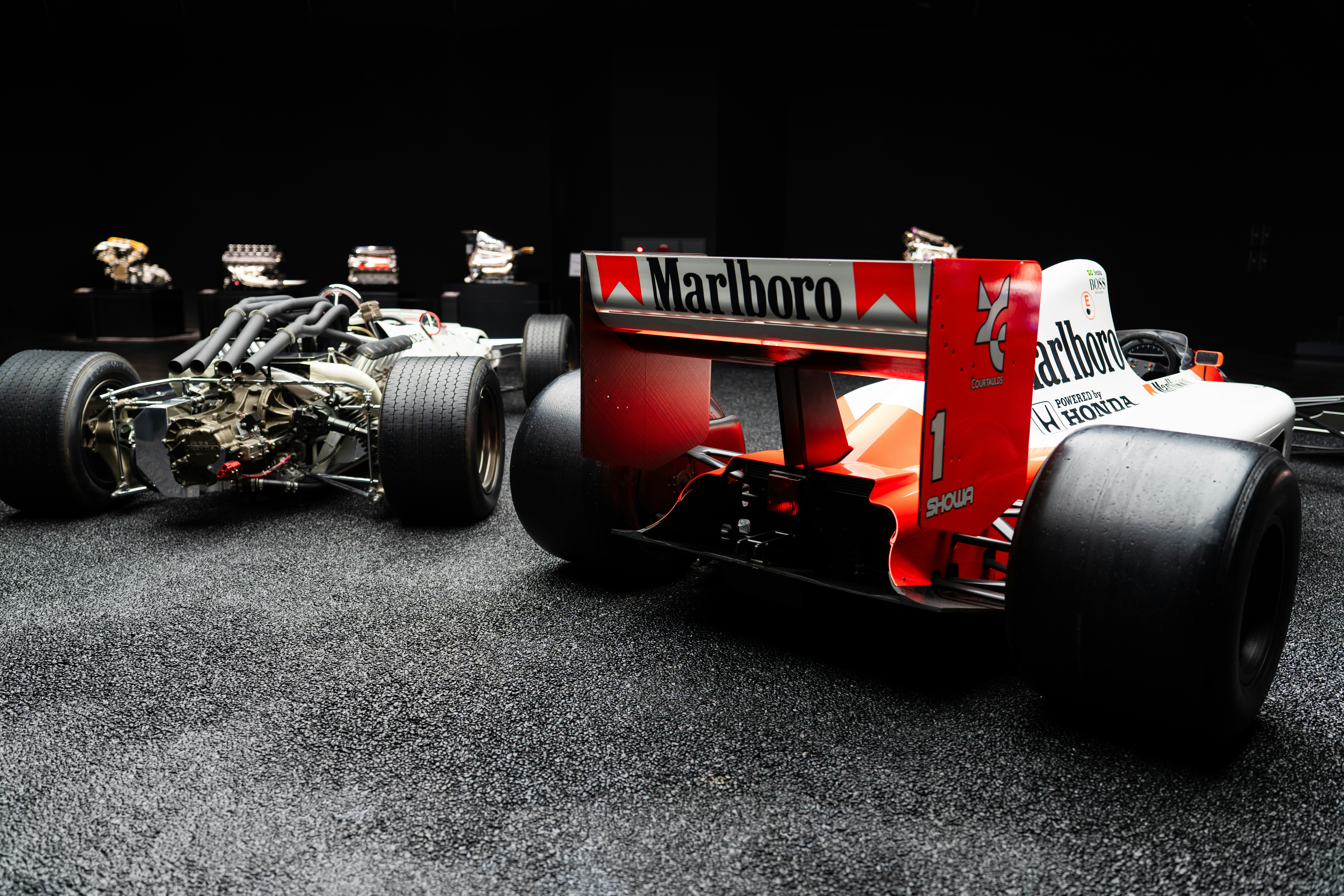 Two formula 1 cars displayed in a dark setting