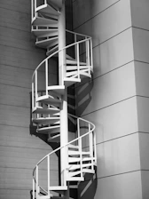 White spiral staircase against a modern building wall