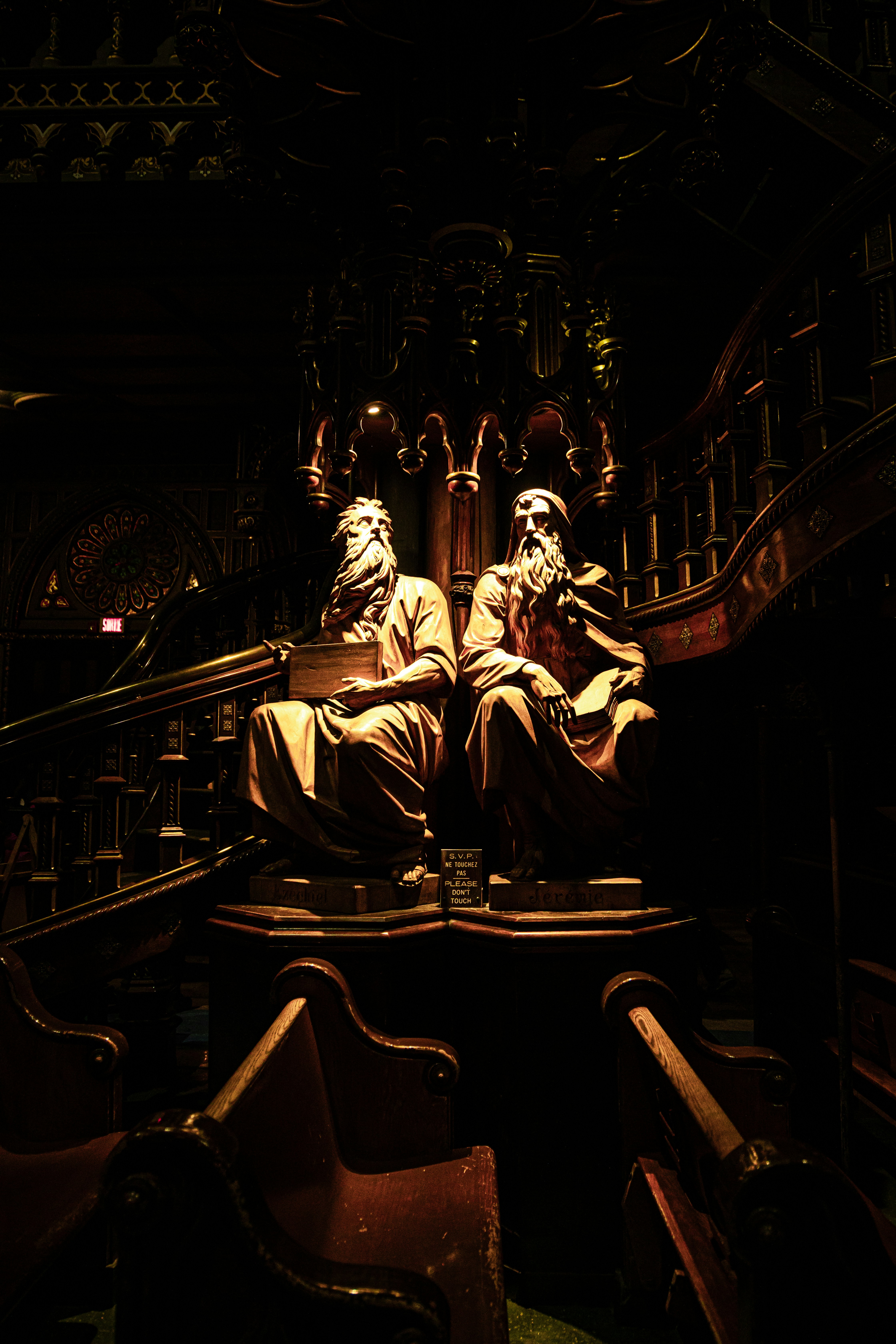 Two seated statues in a dark, ornate interior.