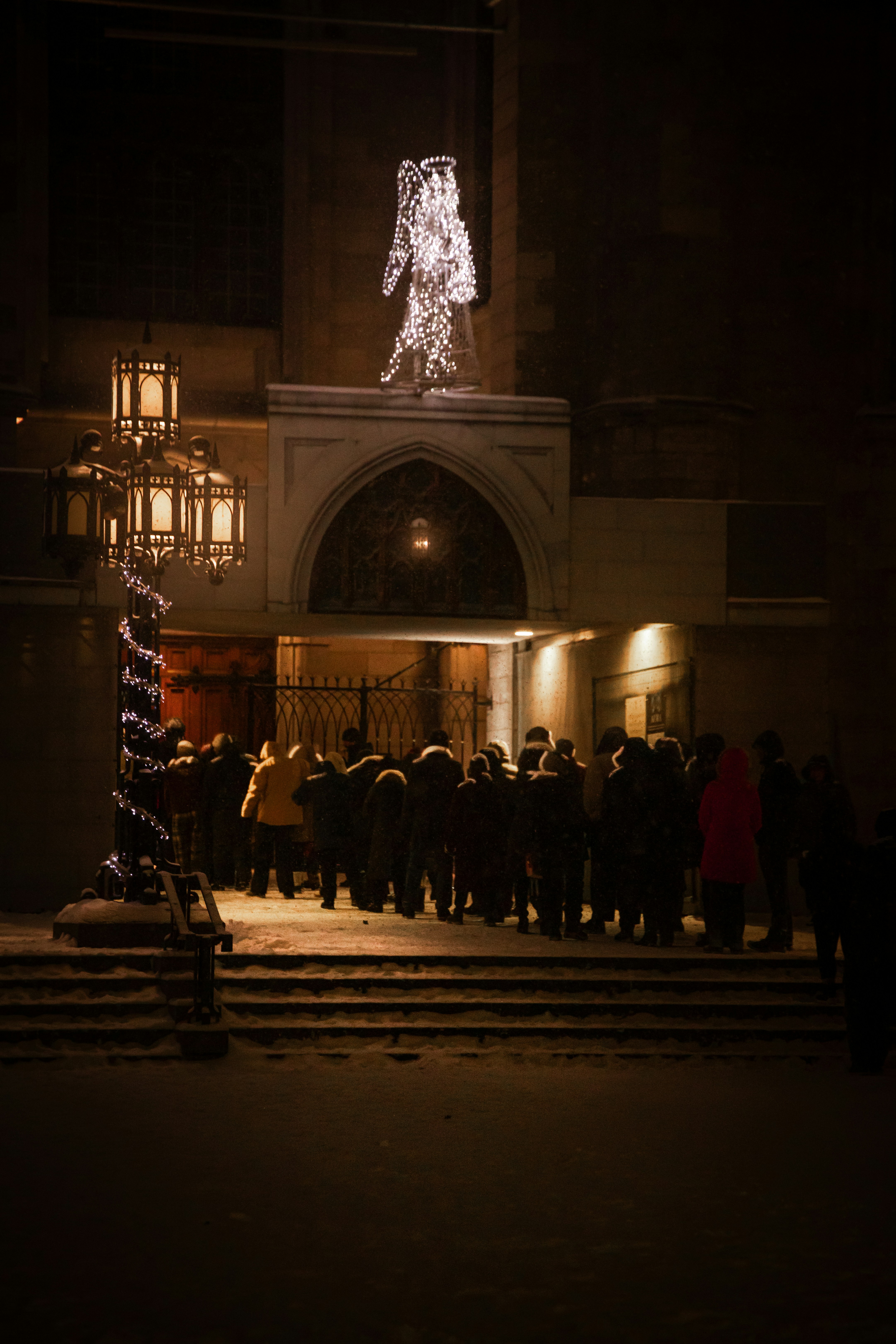 People gather outside a building decorated with lights