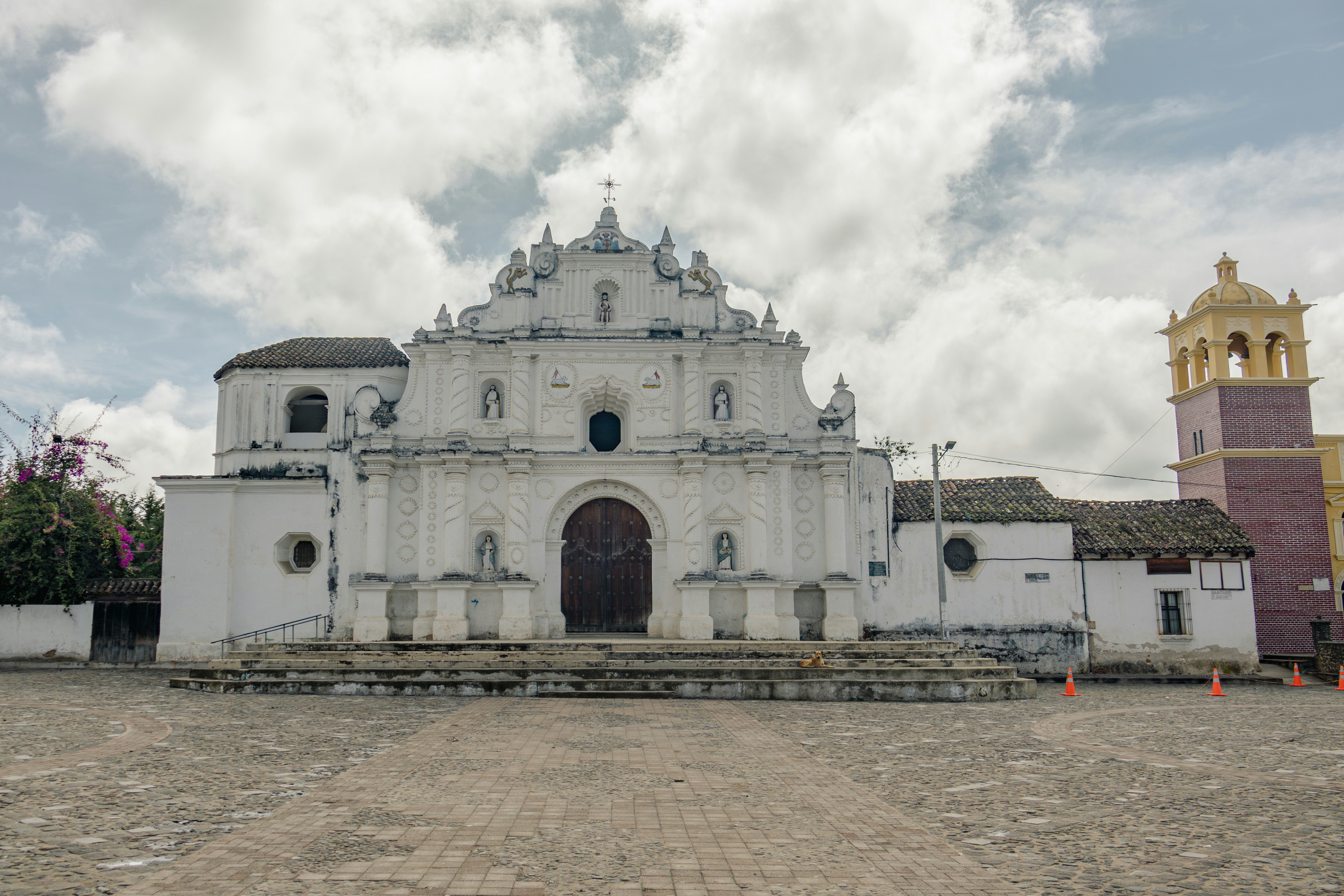 White baroque church with a bell tower under clouds