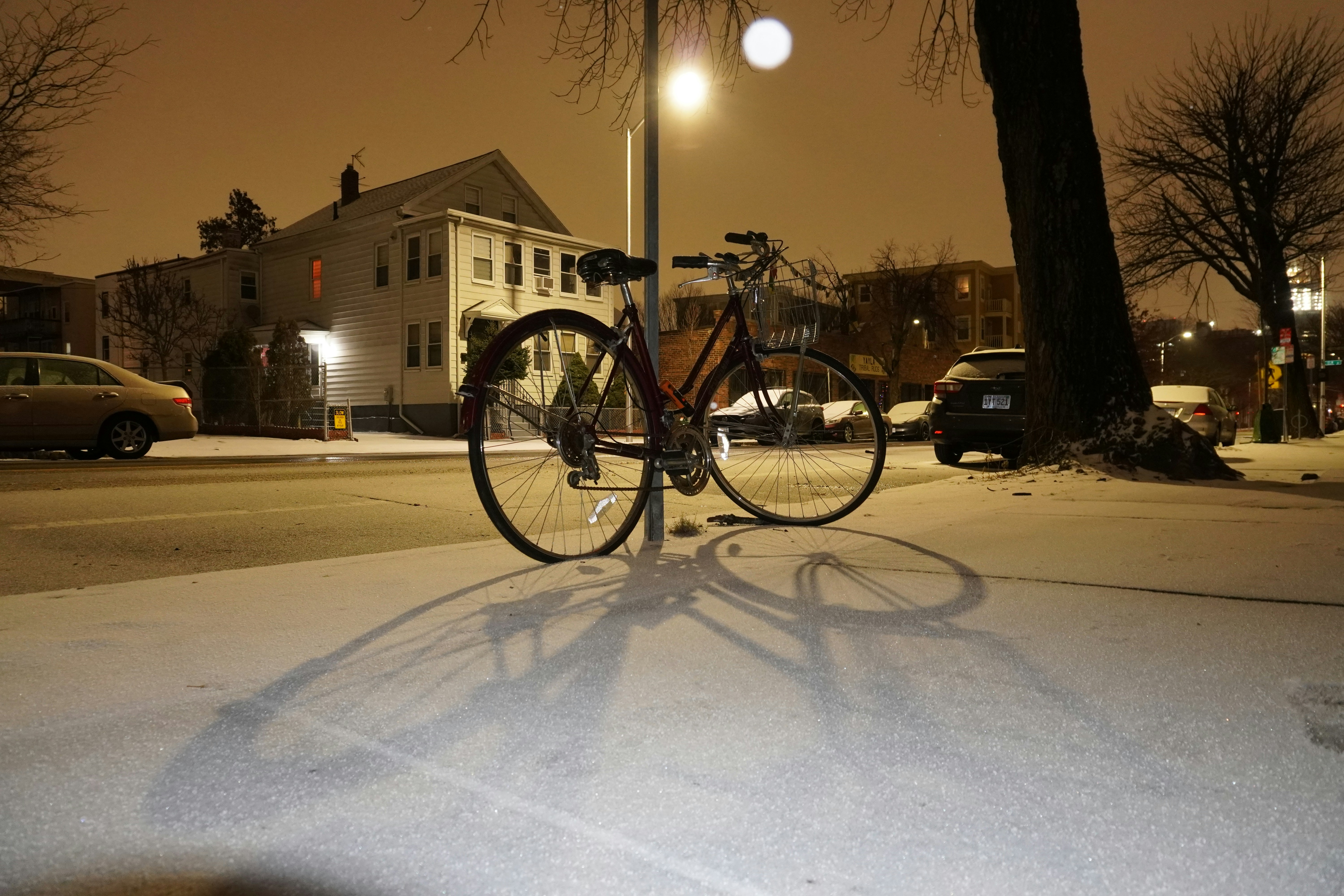 Bicycle parked on a snowy street at night.