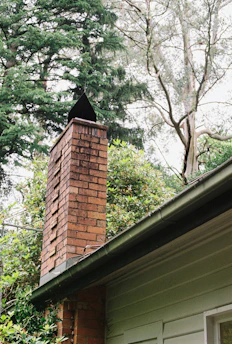 Brick chimney on a house surrounded by trees