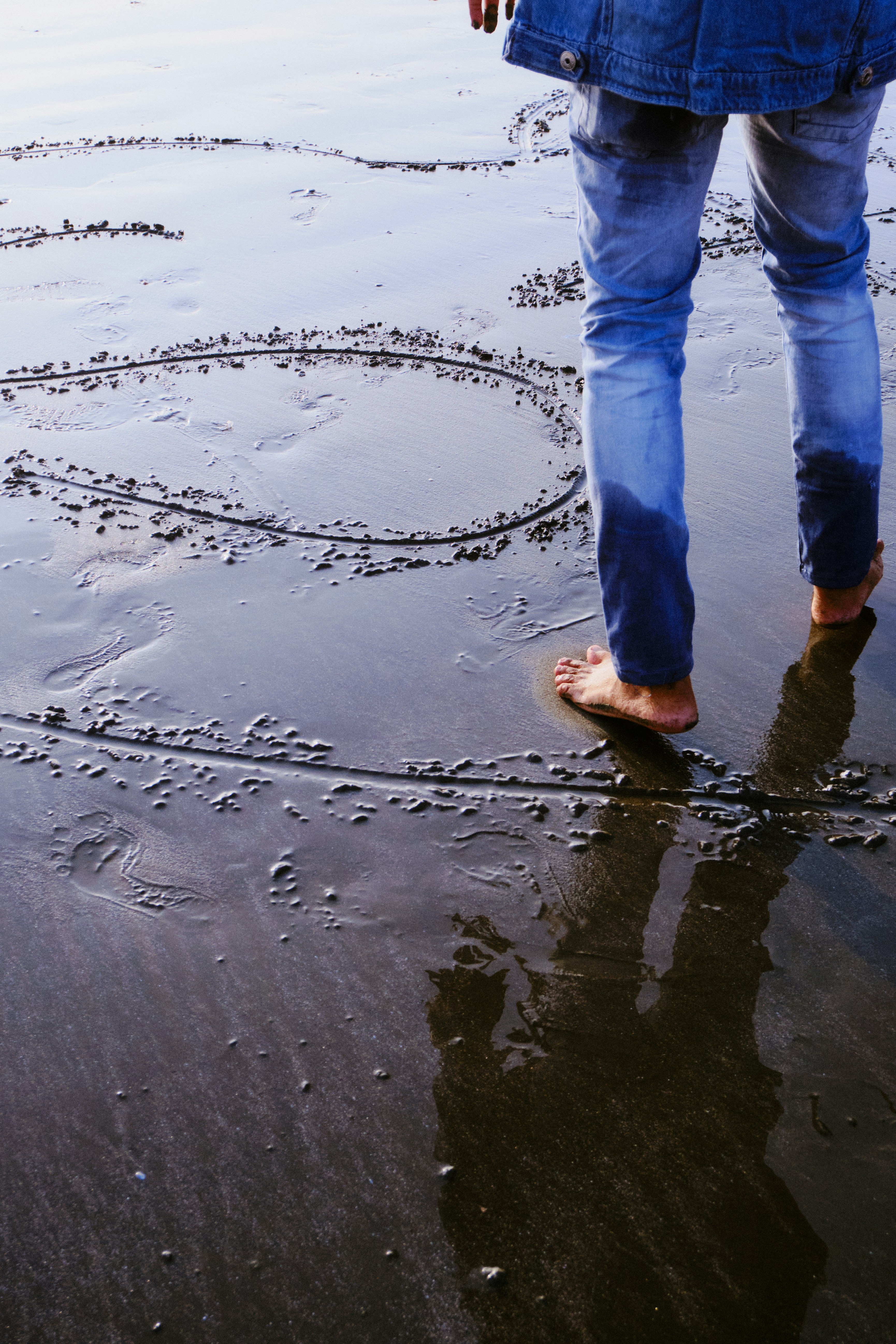 Pessoa desenhando forma de coração em areia molhada na praia