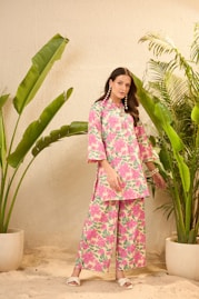 Woman in floral print outfit standing near plants