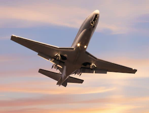 A private jet ascends into a colorful sunset sky.