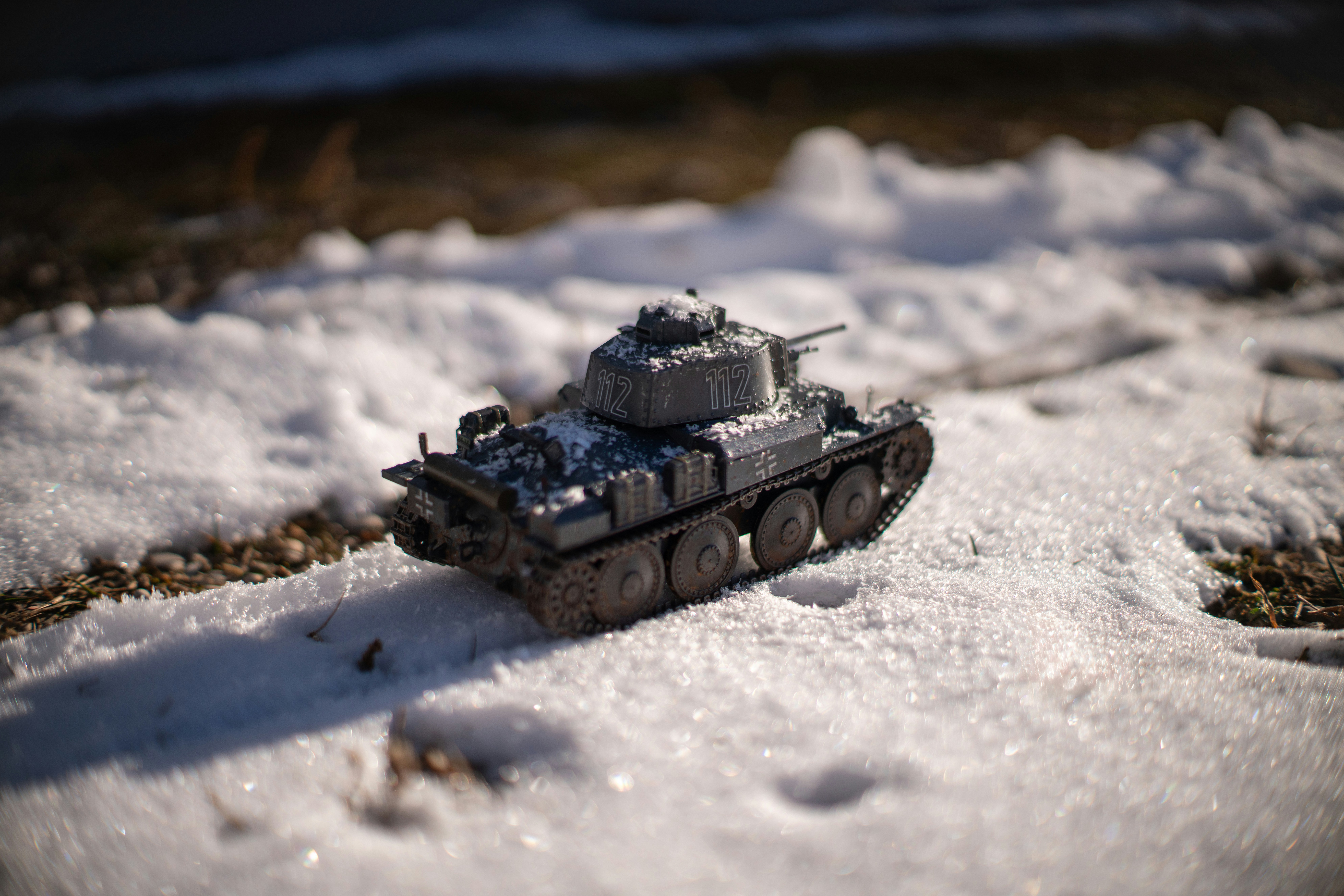 A small toy tank sits in the snow.