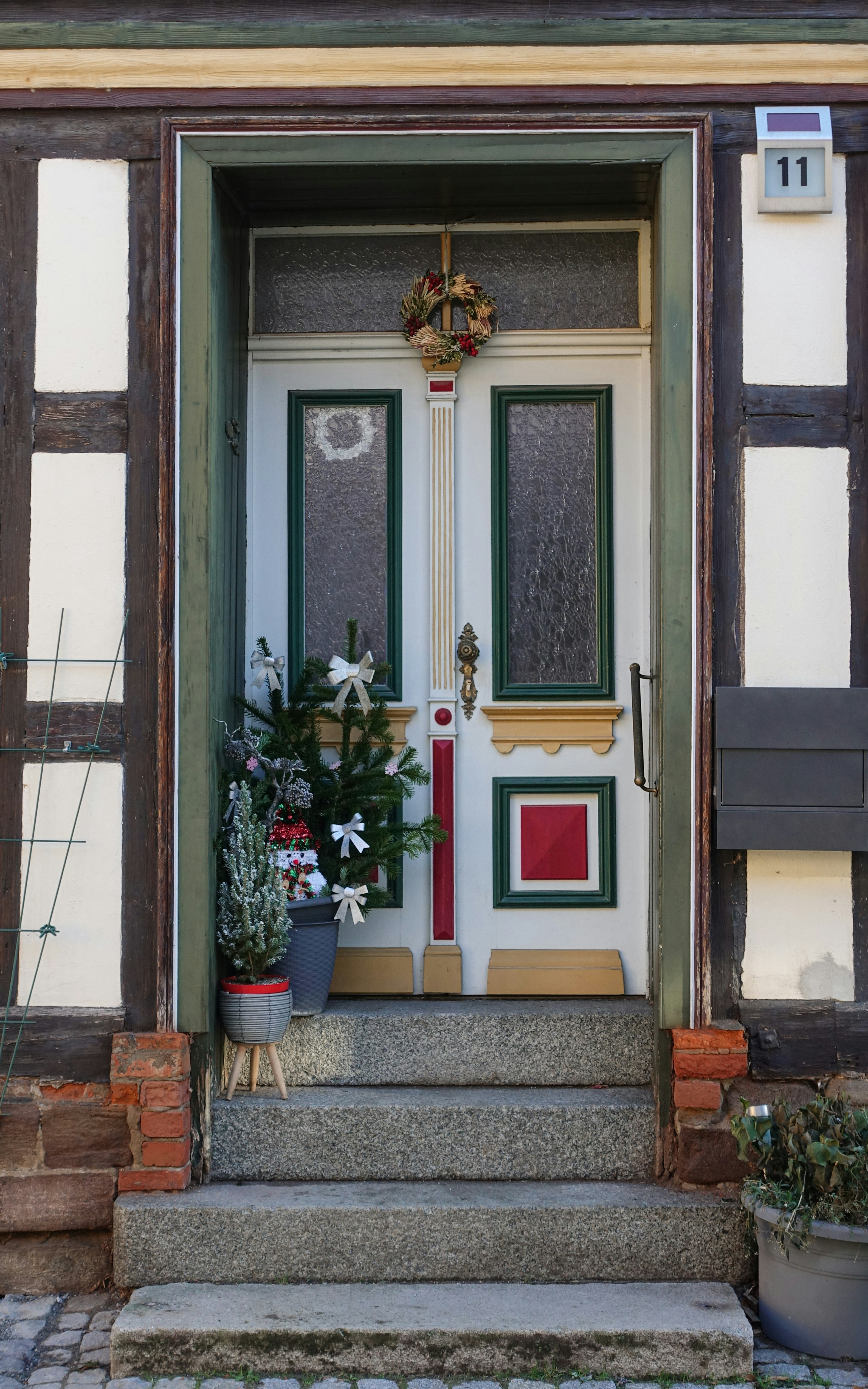 Uma árvore de Natal decorada está ao lado de uma porta branca.