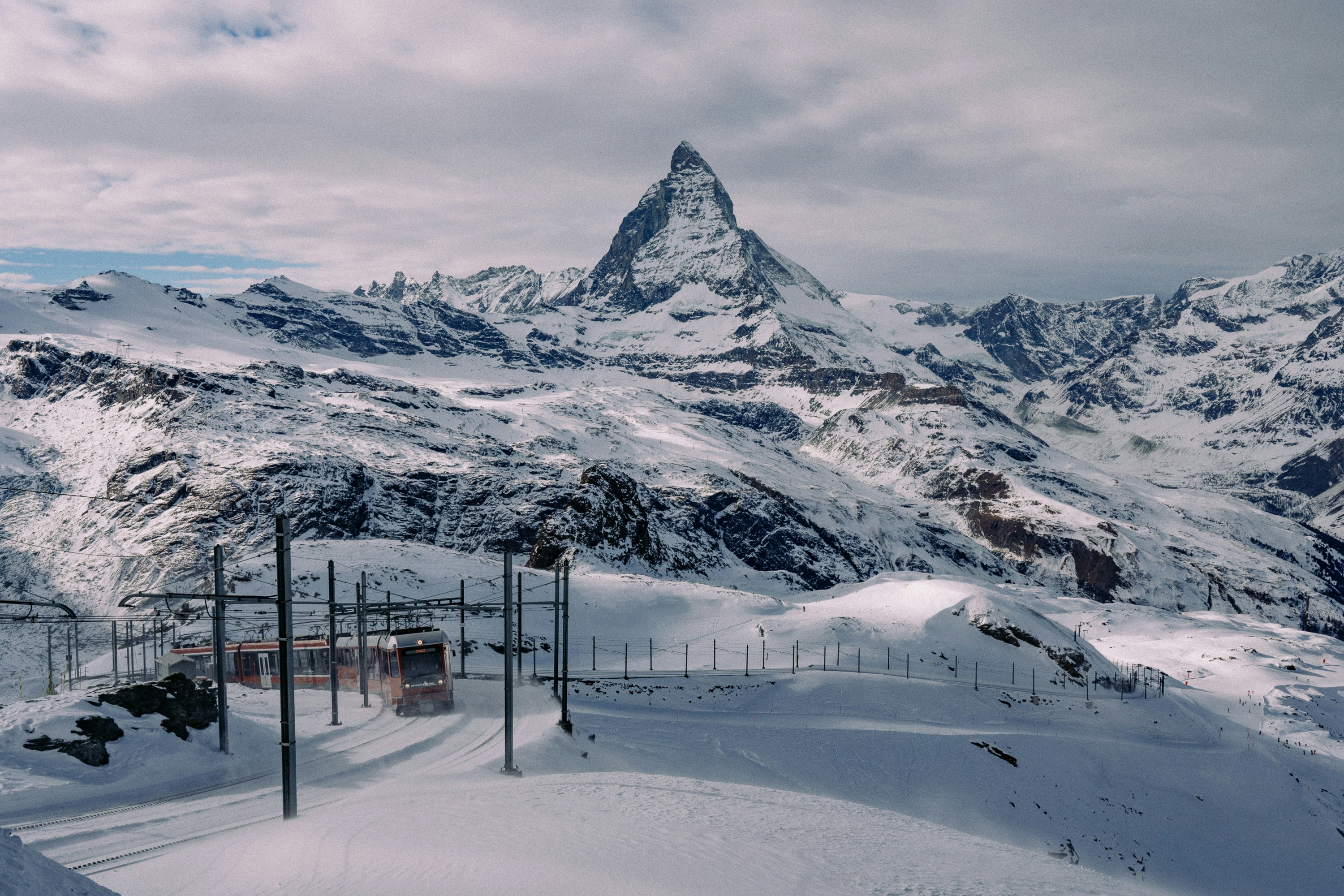 Snow-covered matterhorn mountain under a cloudy sky.